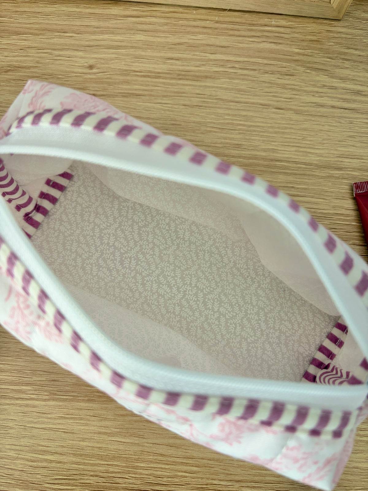 Close-up of pink floral bag interior with purple striped trim and beige lining