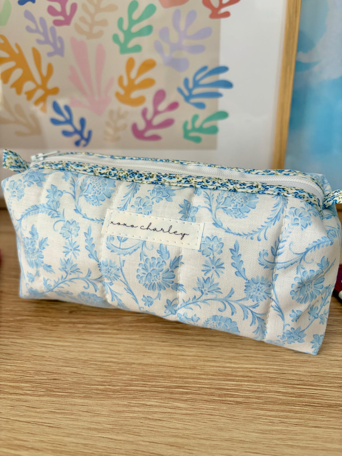 Blue floral cosmetic bag with top zipper and light trim edging