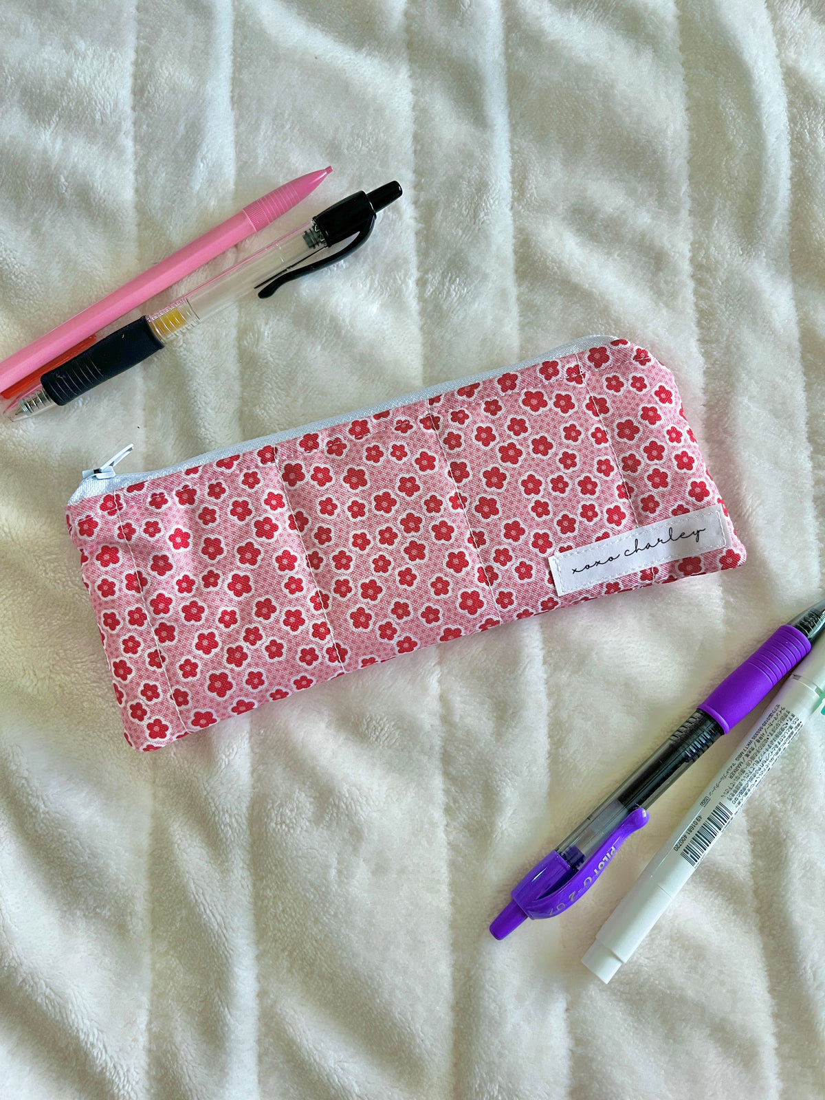 Rectangular pink floral glasses case with white label, zipper closed