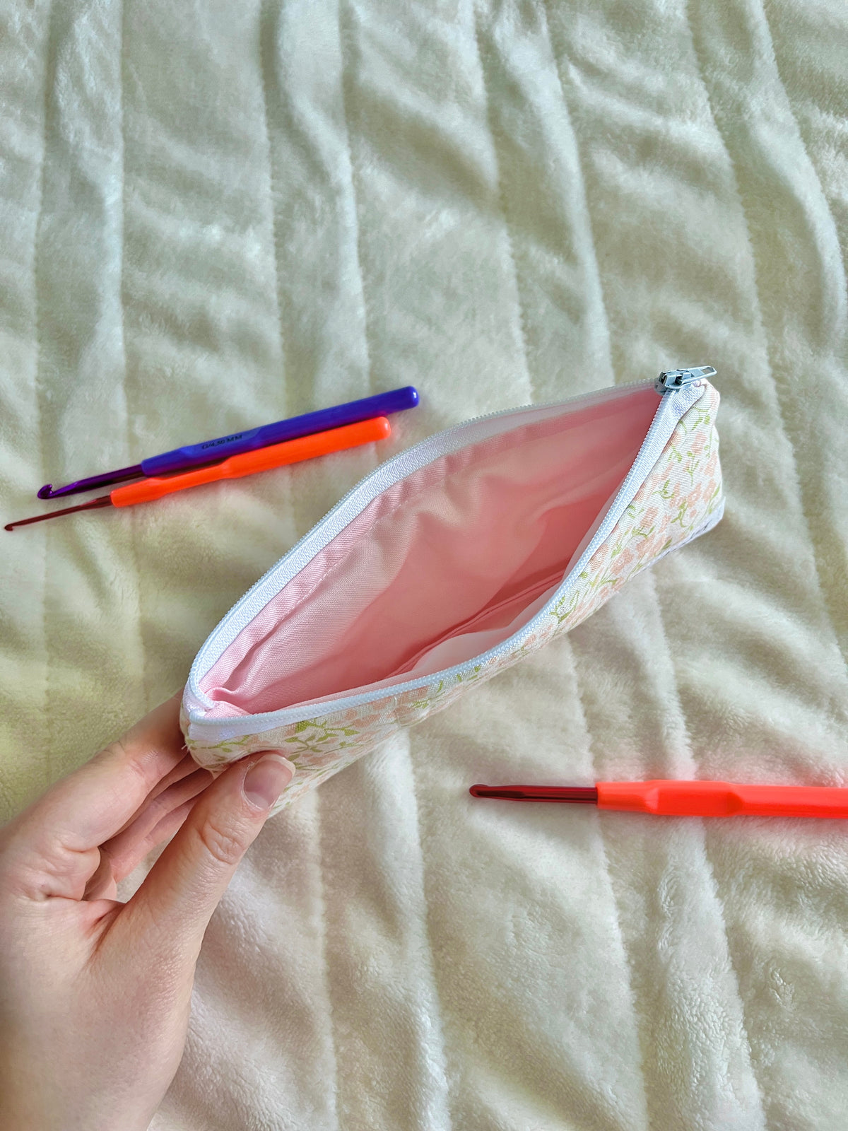 Floral zip glasses case with pink lining, open top held in hand