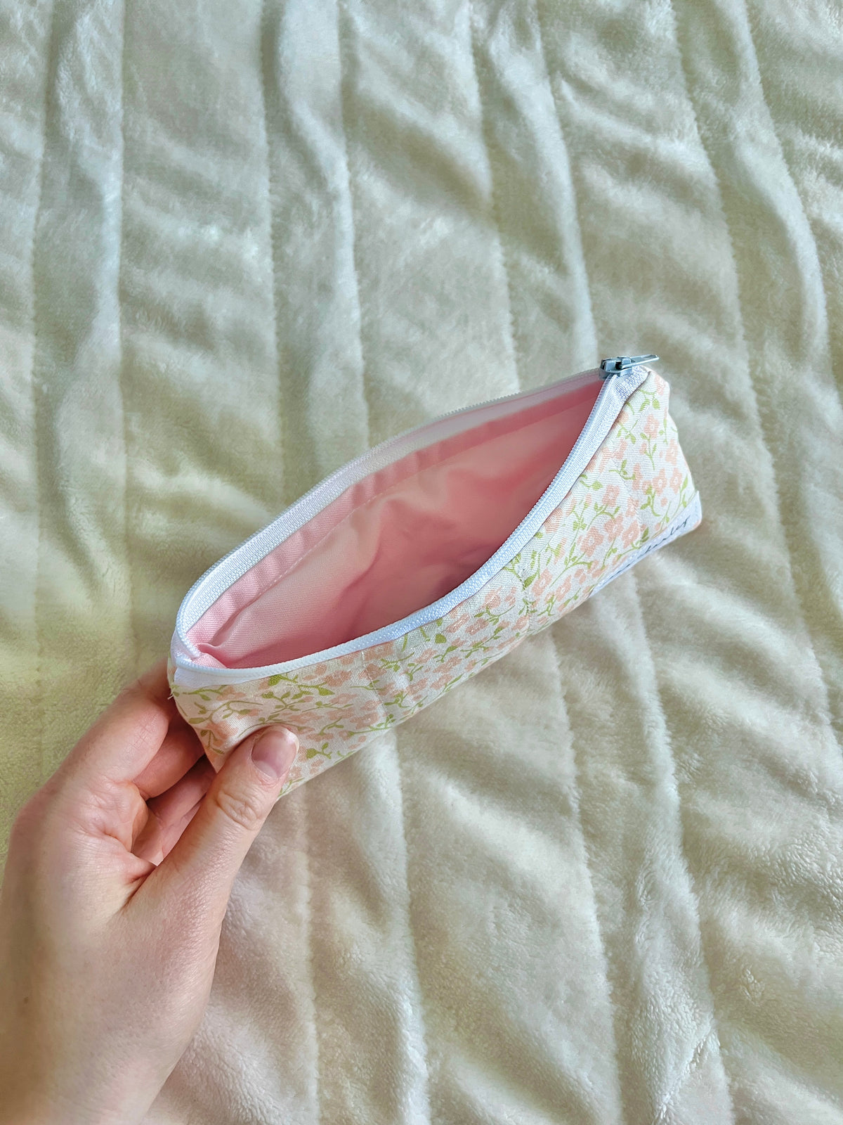 Floral zip glasses case pouch with pink interior, angled in hand