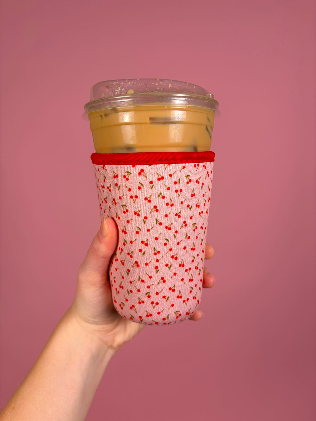 Medium sweet cherry cup sleeve with red cherry pattern, holds a takeaway cup