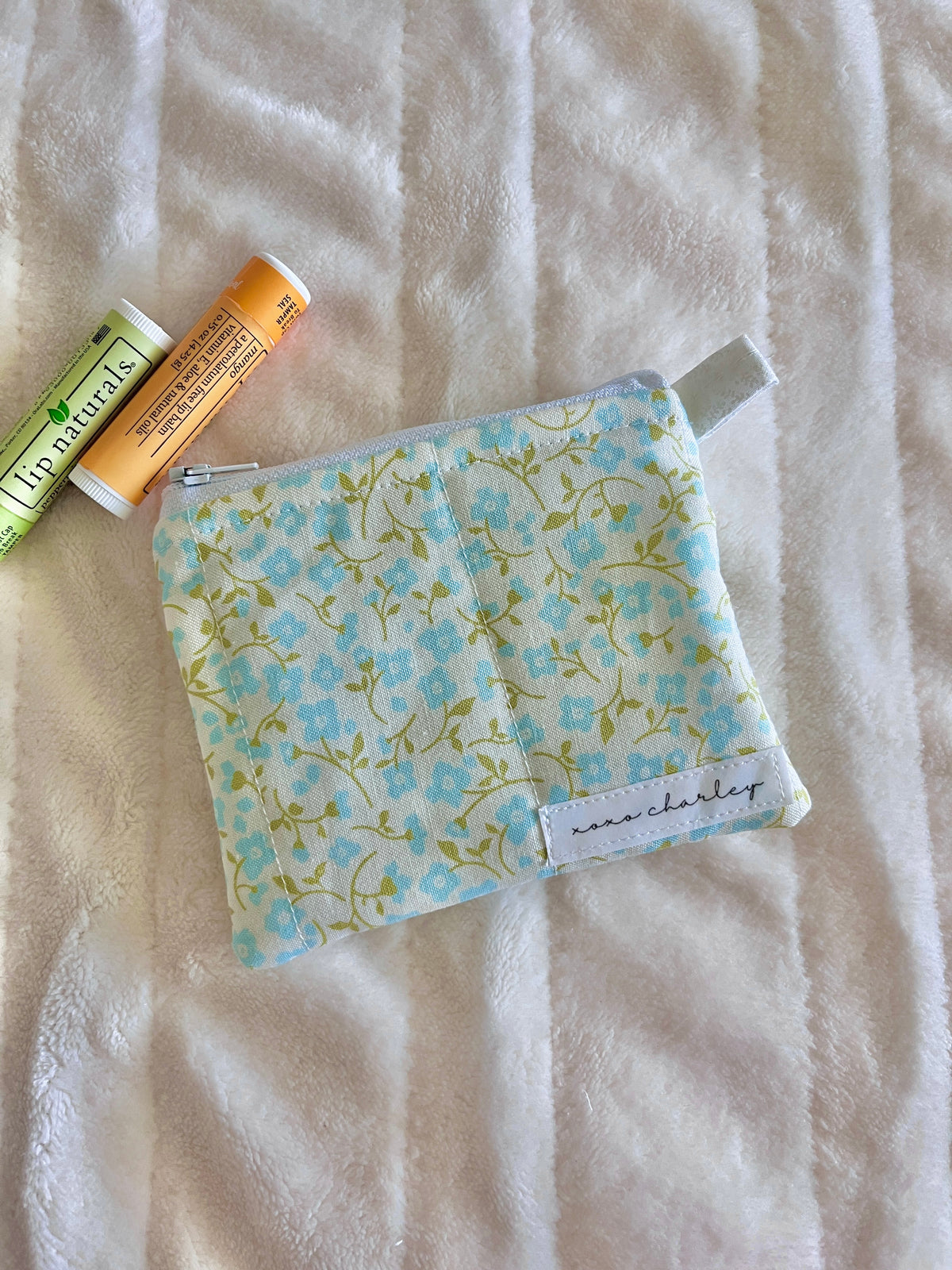 Light blue floral keychain wallet pouch with zipper and fabric strap label