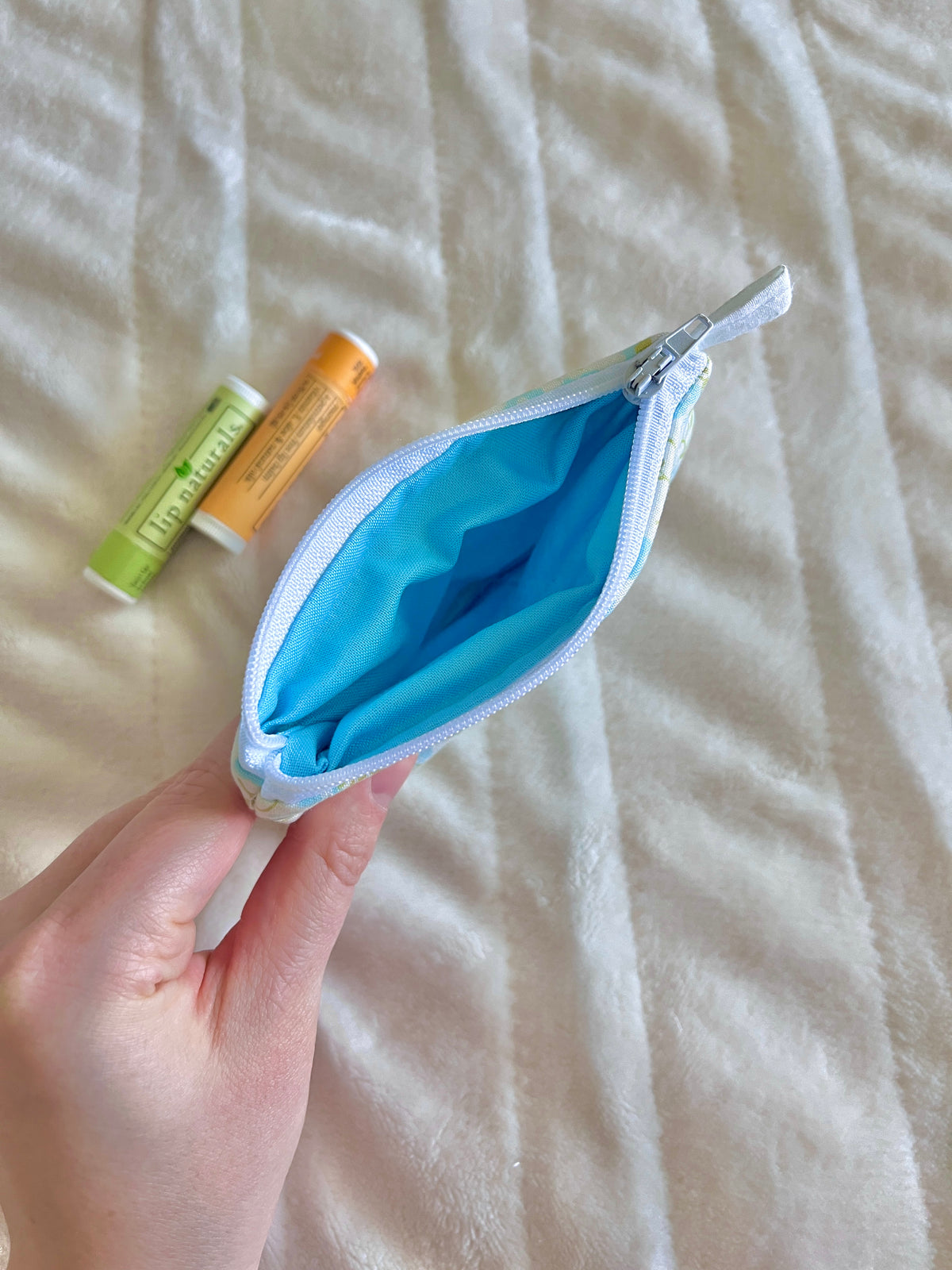 Light blue floral mini pouch wallet with zipper open, showing bright blue interior