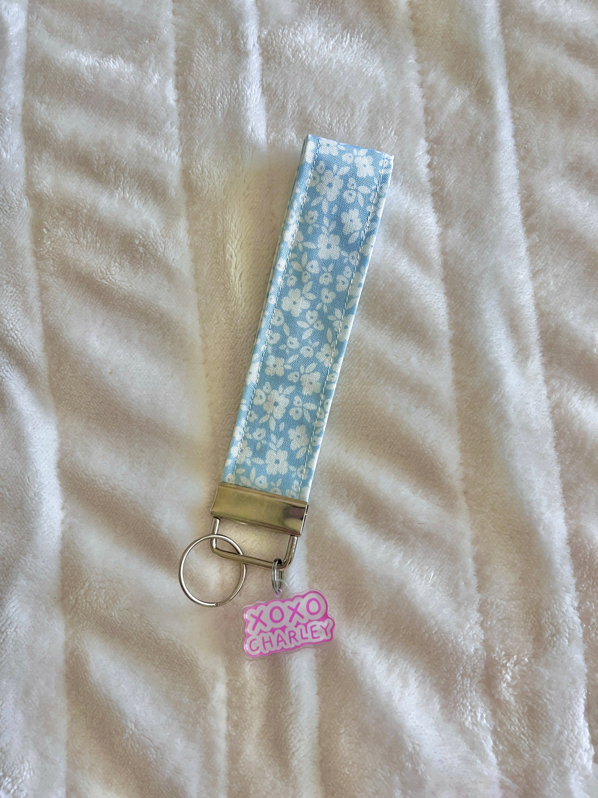 Blue floral wrist keychain with metal clasp and pink 'XOXO' charm