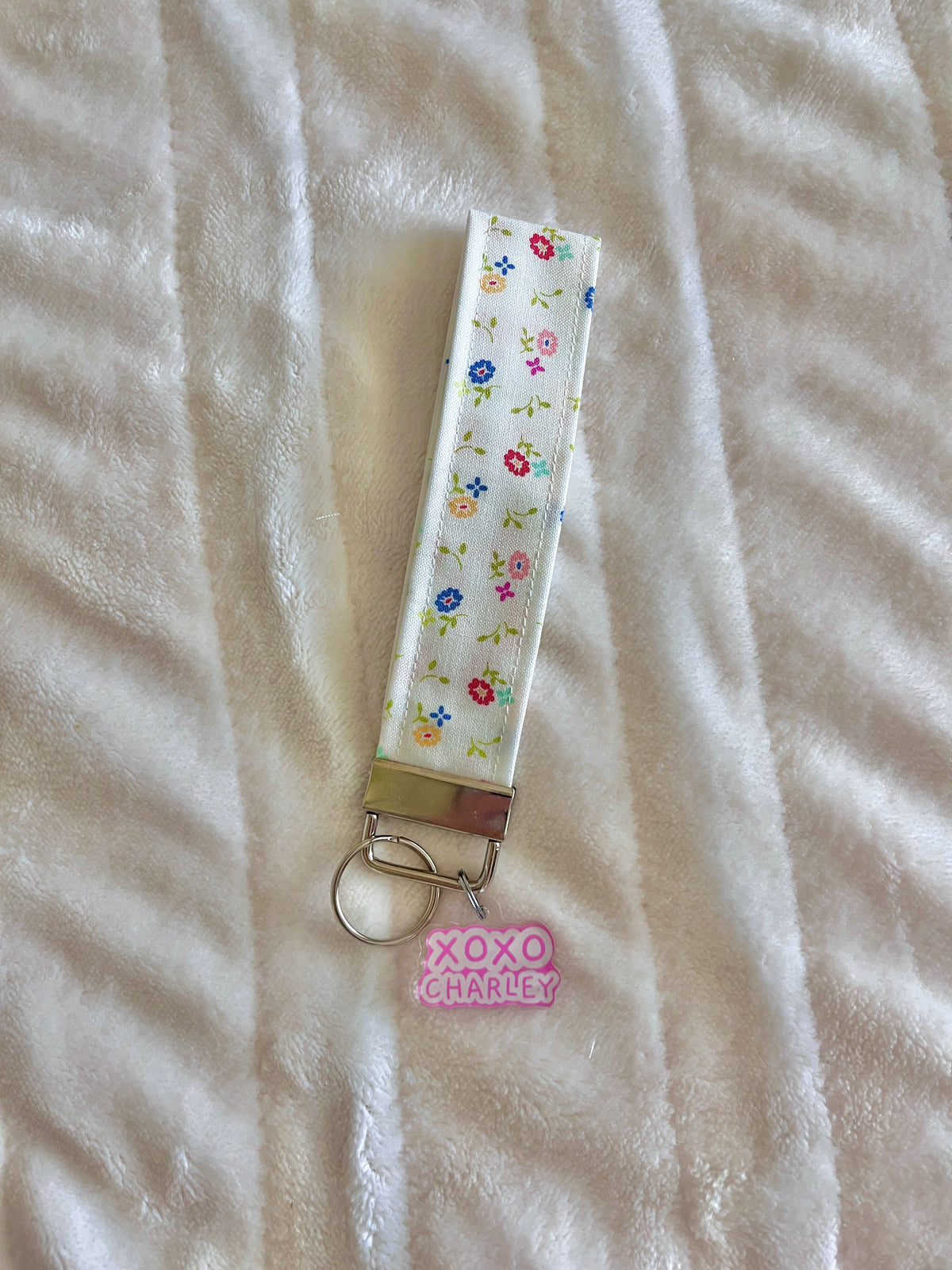 Delilah keychain wristlet with floral strap, metal clasp, and pink logo charm