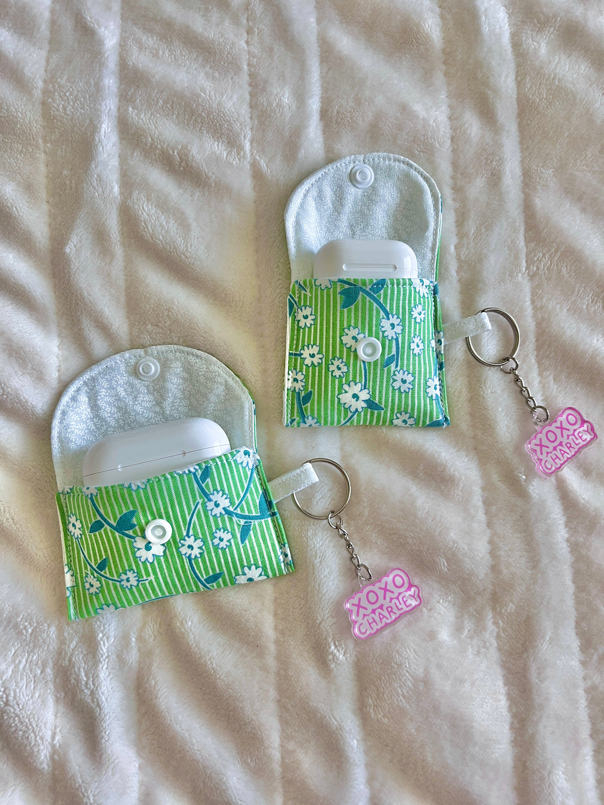 Green floral earbud cases with flap top, snap button, and keychain rings