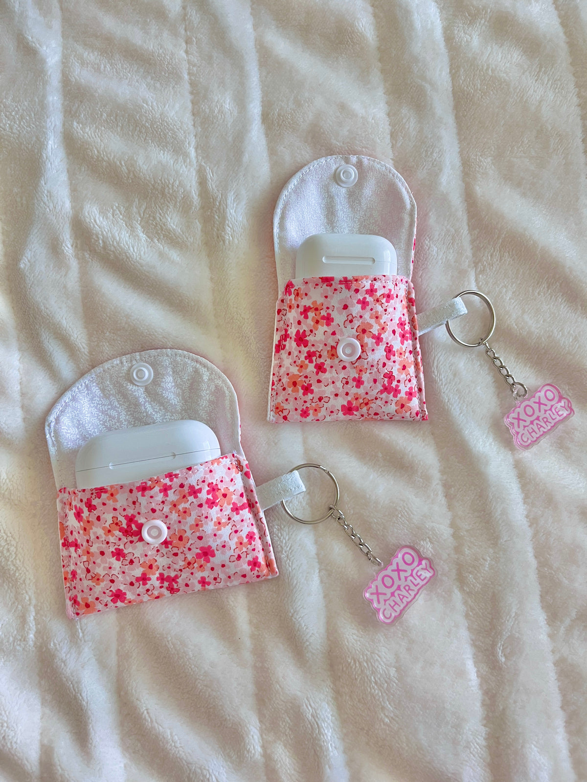 White and pink floral earbud cases with button flap and keychain rings