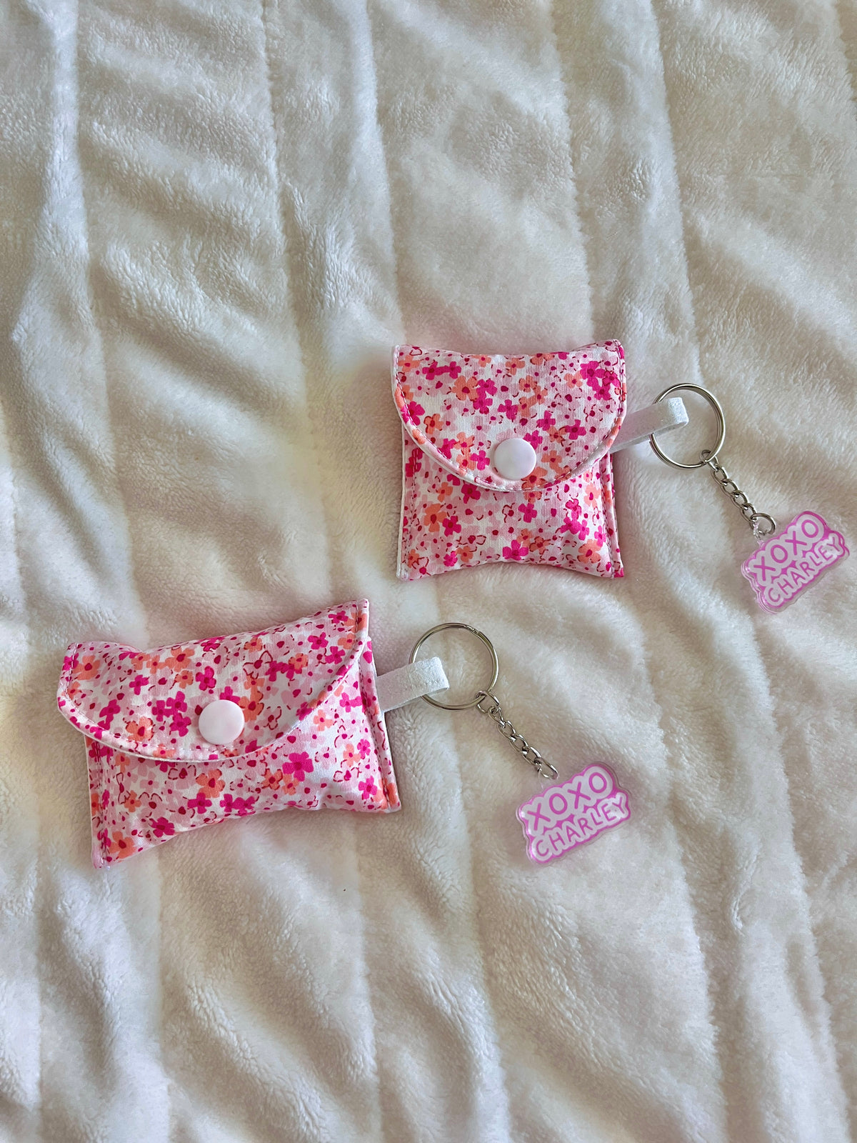 Pink floral earbud case with button flap and keychain ring, small charm