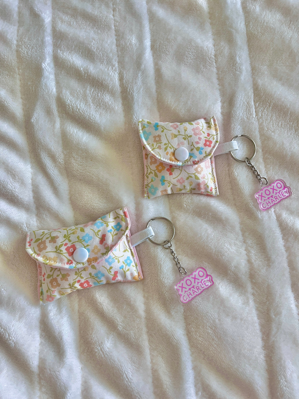 Floral earbud cases with pink flaps, snap buttons, and keychain rings with XOXO charms