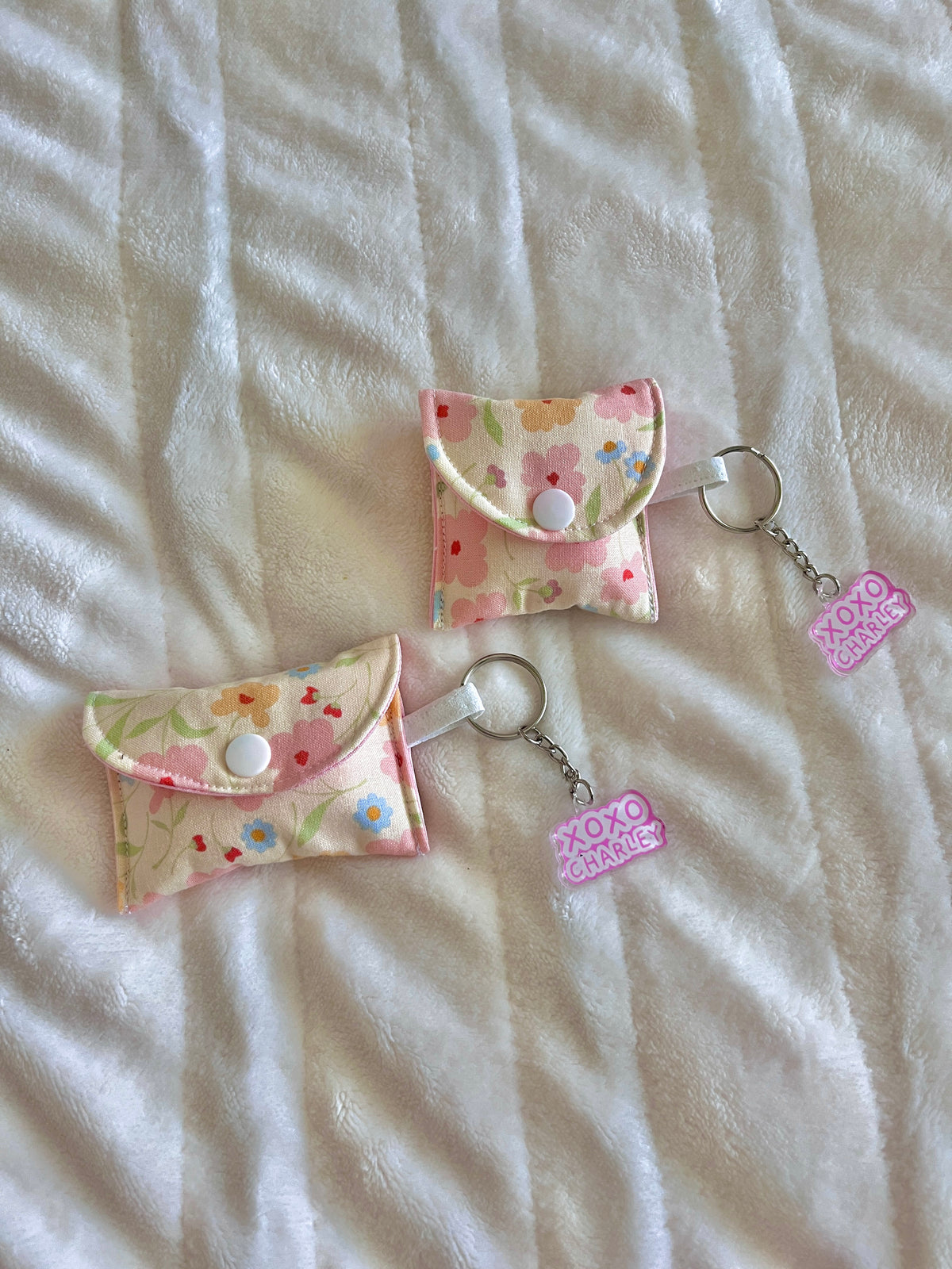 Floral earbud case pouch with pink half-moon top and keyring, two pouches with tags