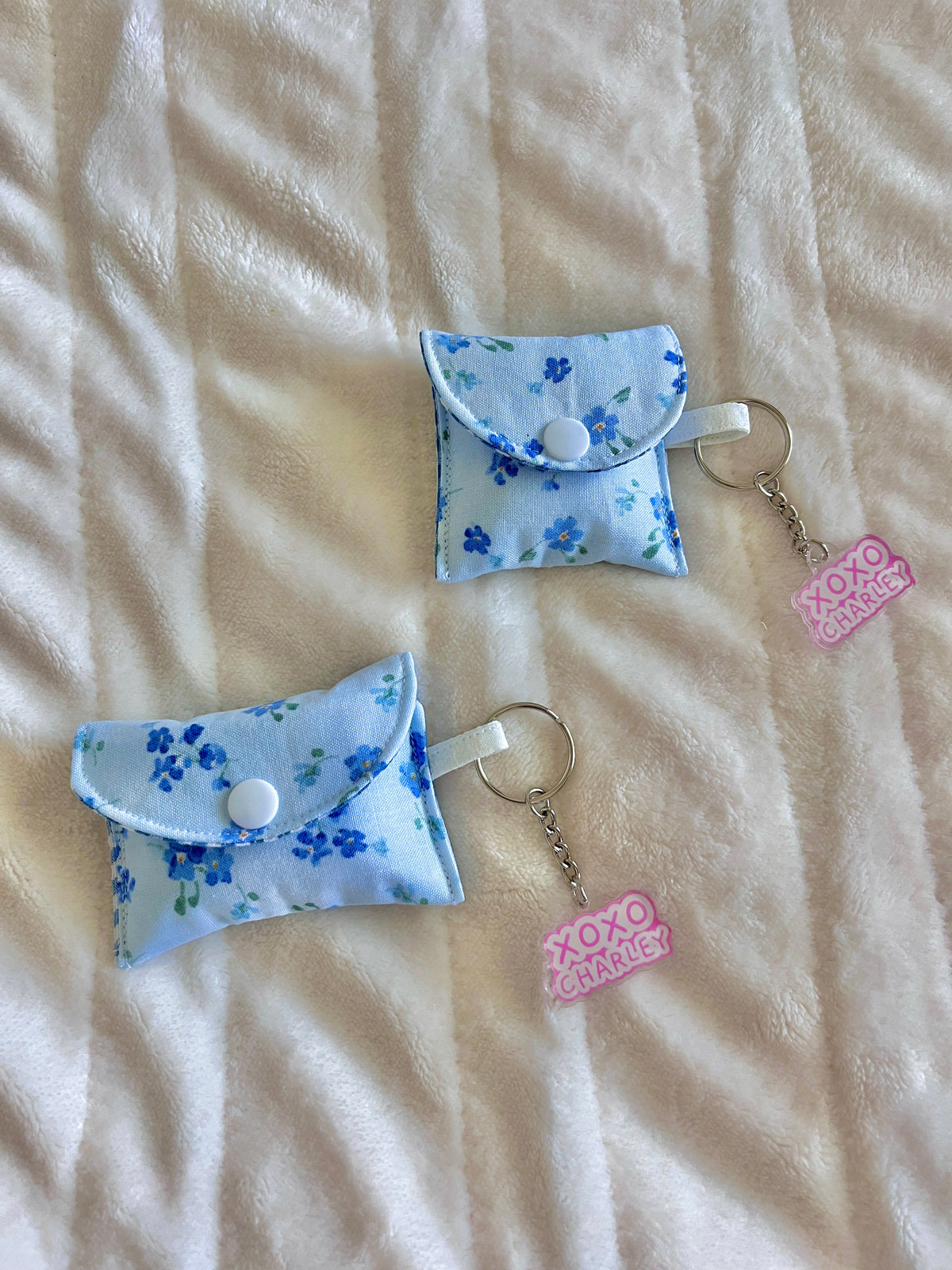 Evelyn earbuds cases with blue floral fabric, gingham flap, and metal keyrings