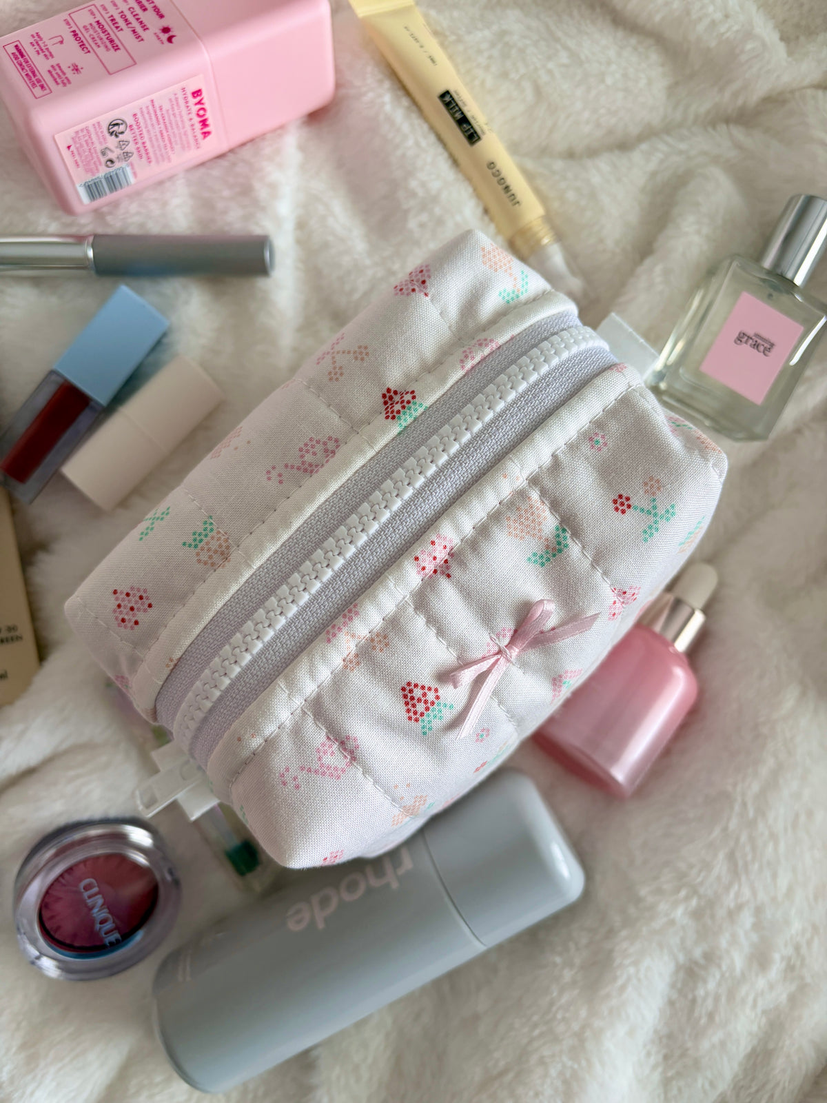 Mini white makeup bag with pastel picnic print and silver zipper, front view