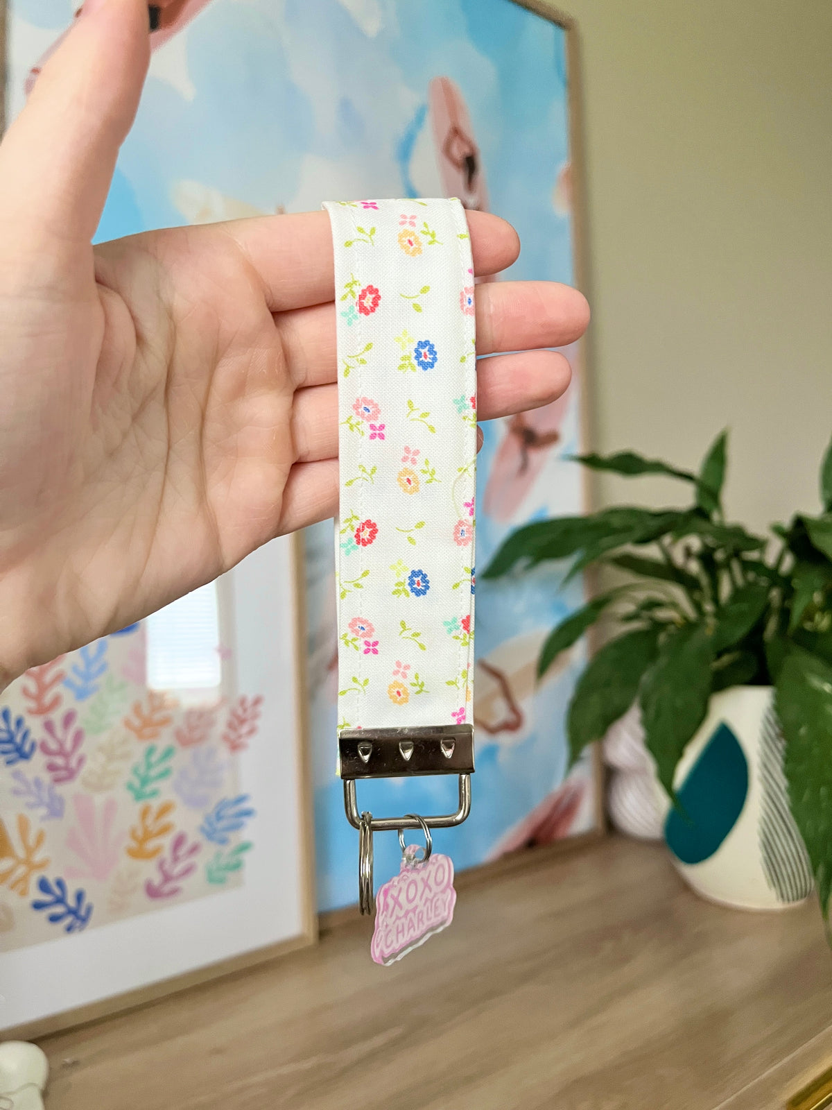 Floral wrist strap with gold buckle and pink keychain charm