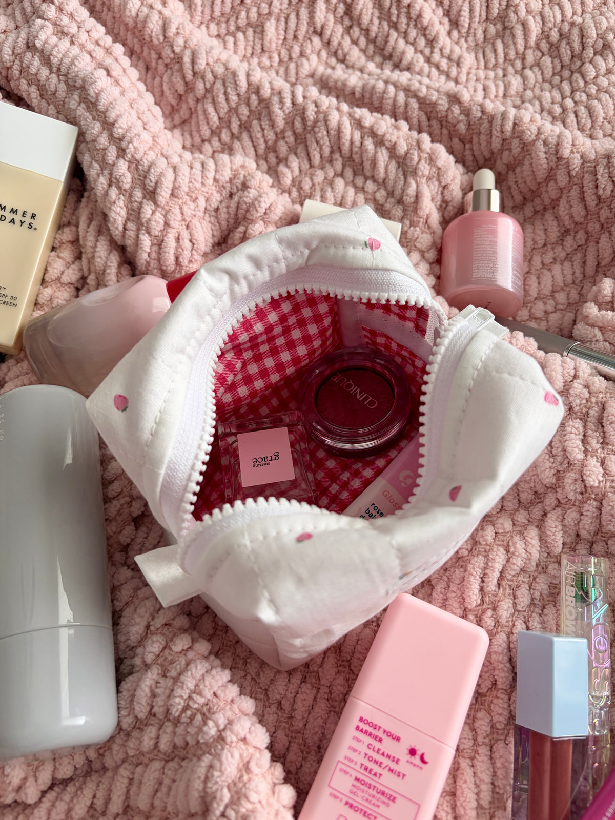 Mini makeup bag opened, cream zipper pouch with red gingham lined interior