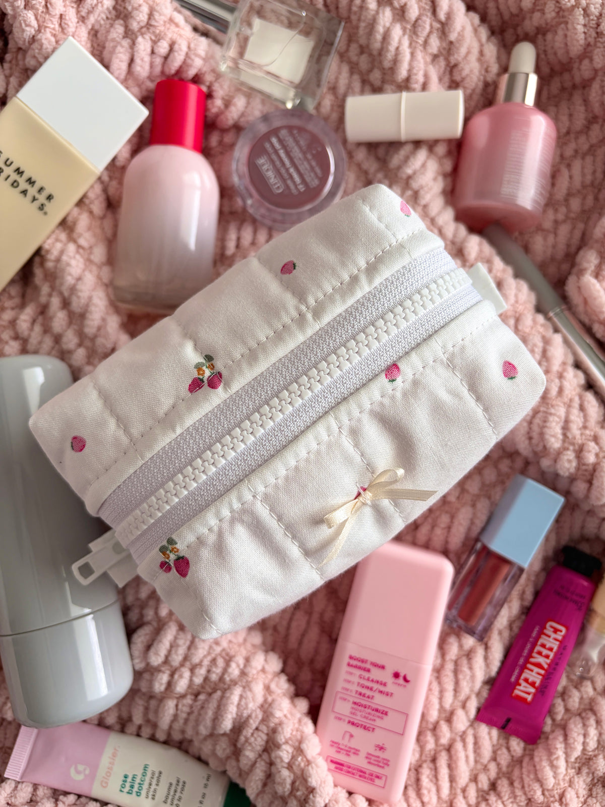 Ivory mini makeup bag with embroidered fruit pattern, ribbon bow, and twin zipper