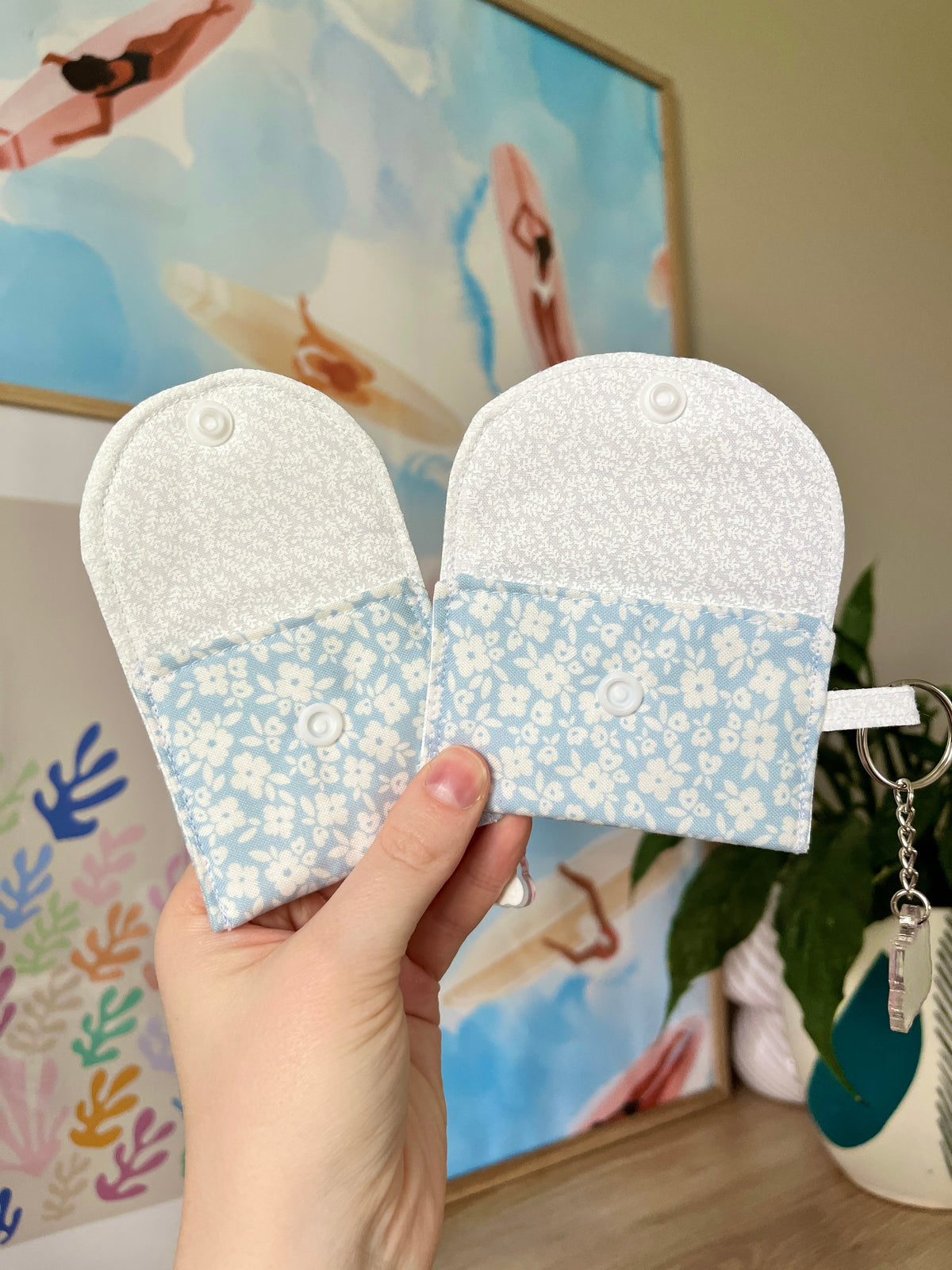 Two floral earbud cases with textured backing, circular button, and key rings