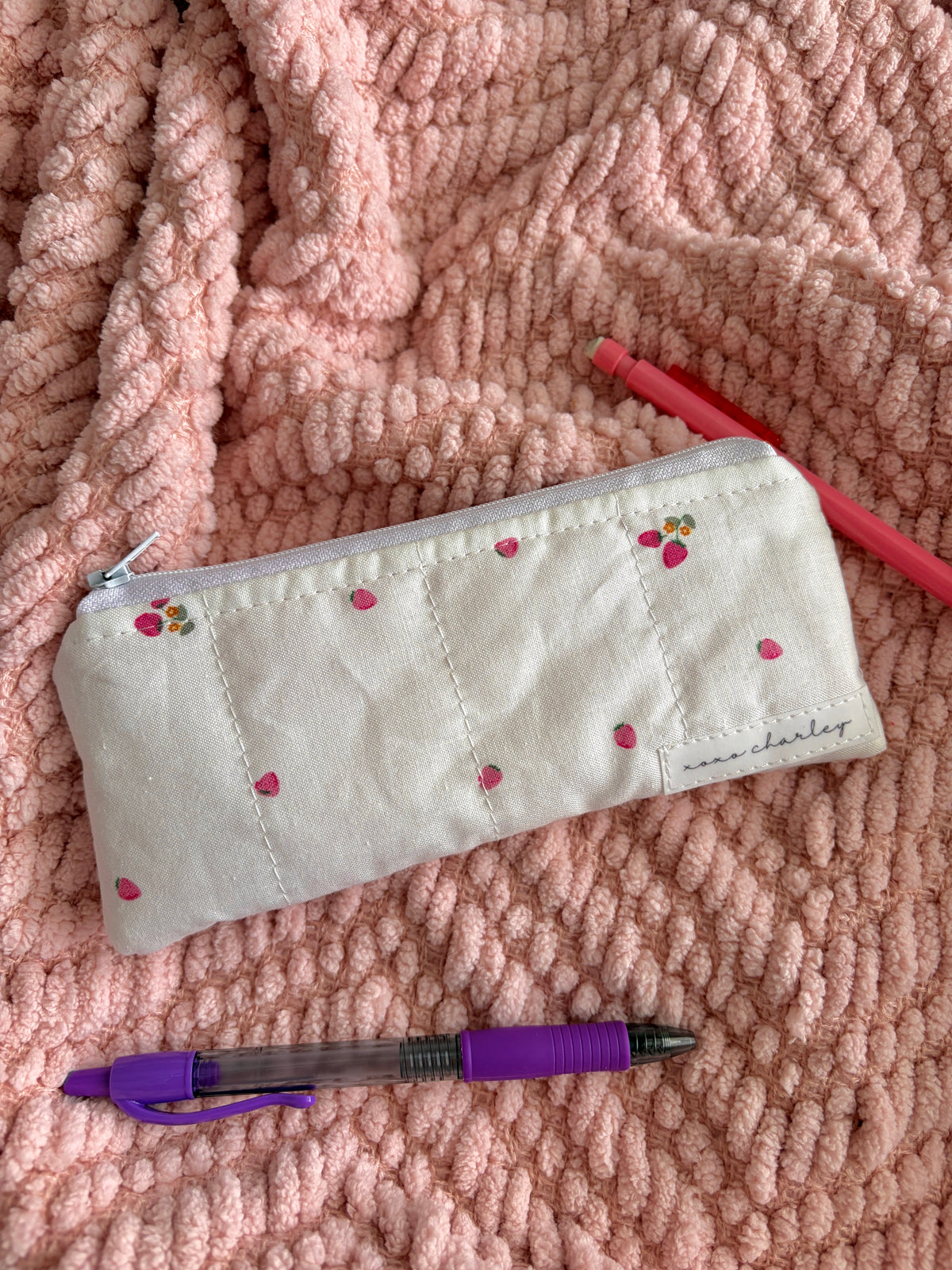 Cream pencil and glasses case with berry print, zipper, and stitched label