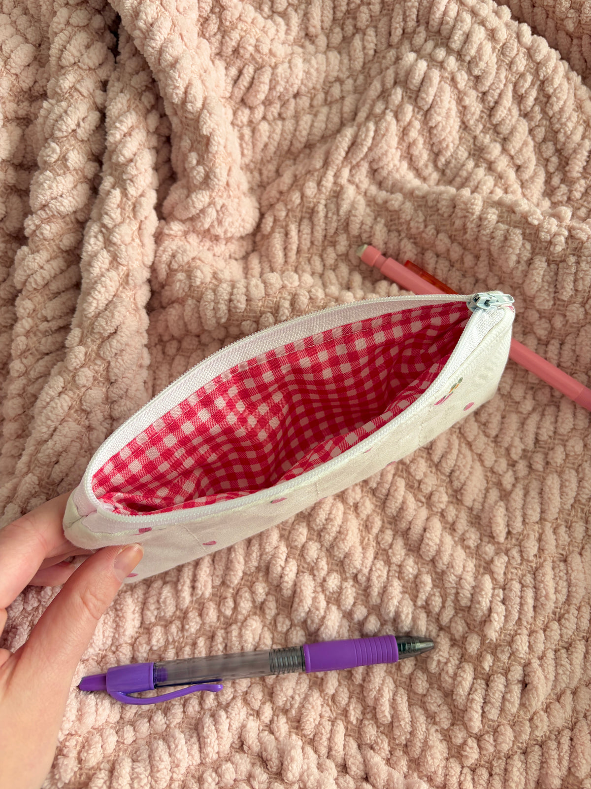 Cream pencil and glasses case opened, showing red gingham lining and zipper edge