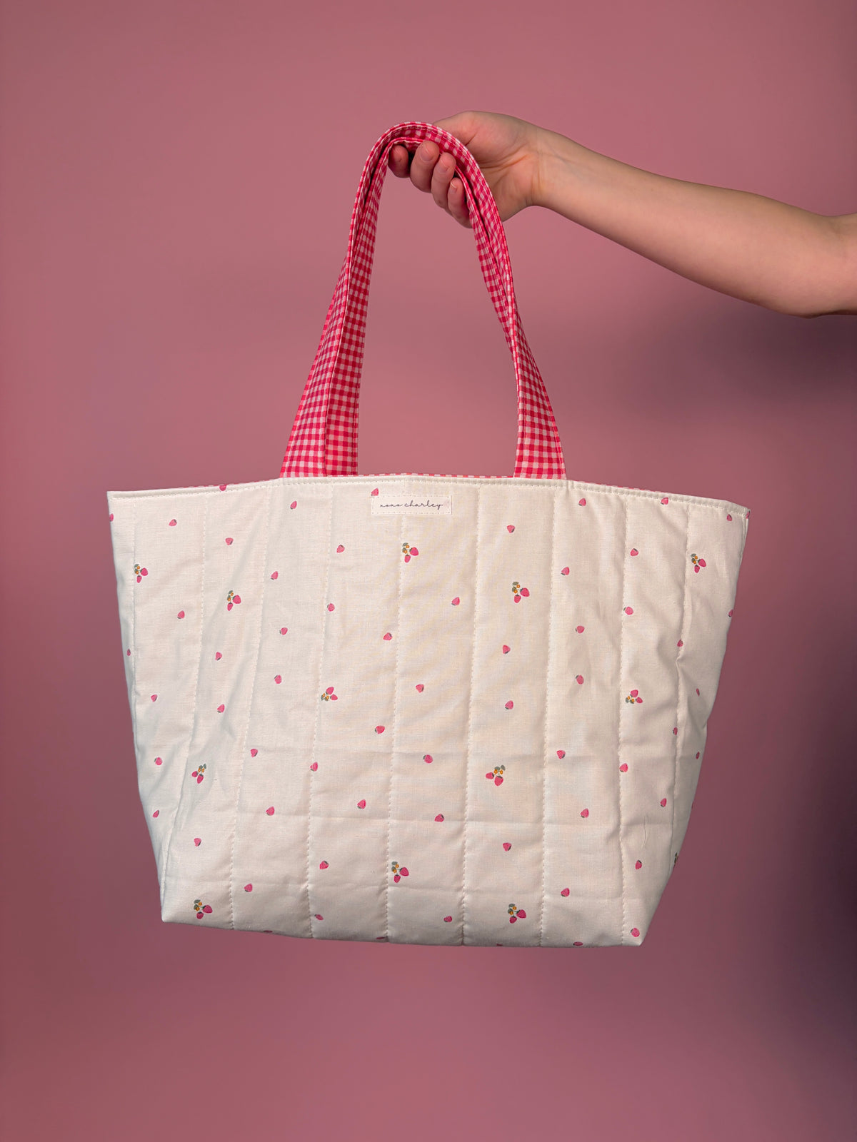 Large tote bag with white body and red gingham handles, scattered berry flower print