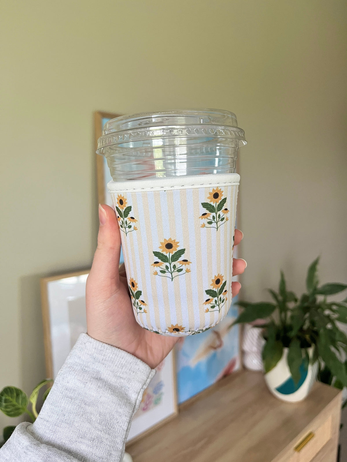 Sunflower and striped cup sleeve with floral stems, held in hand