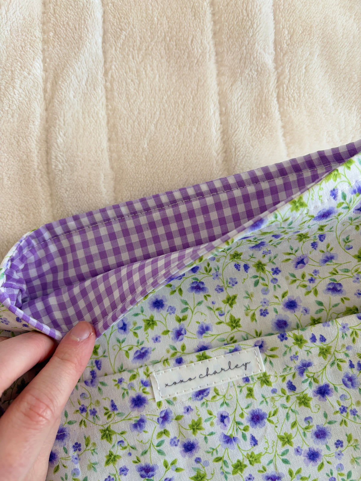 Purple gingham-lined e-reader/book sleeve with floral fabric and stitched label