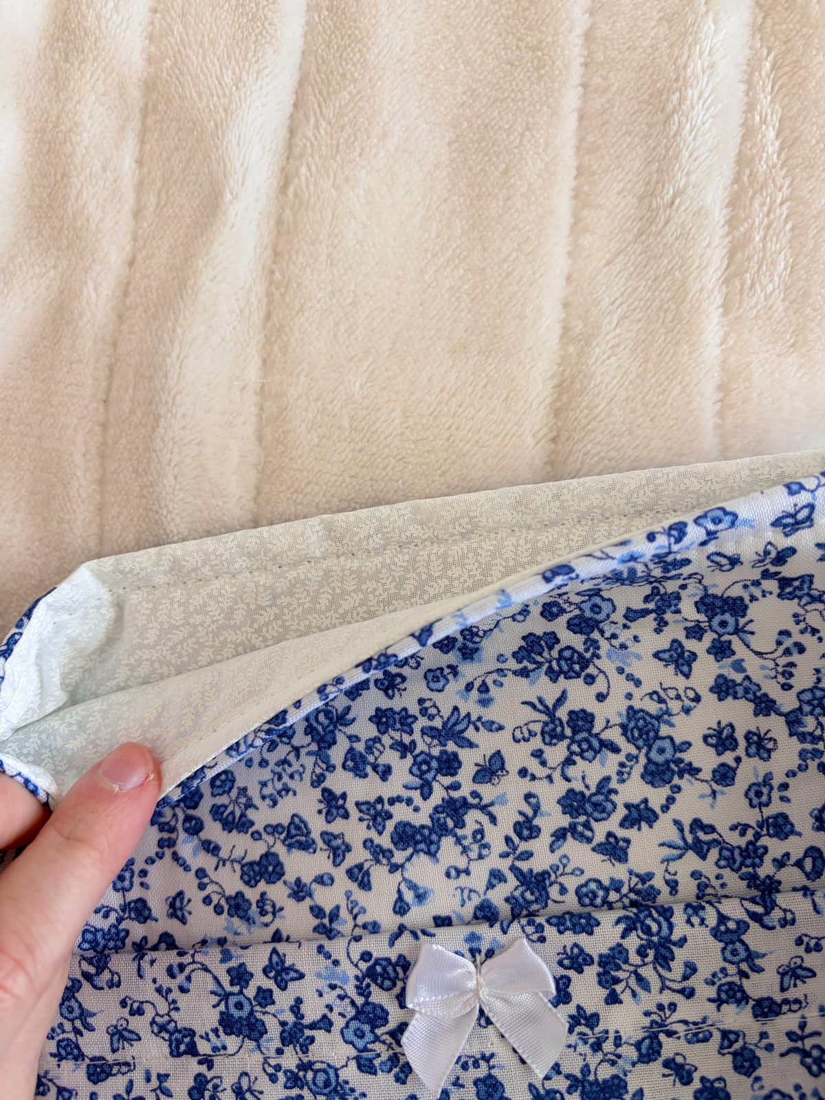 Blue floral fabric e-reader/book sleeve with white bow detail, close-up view