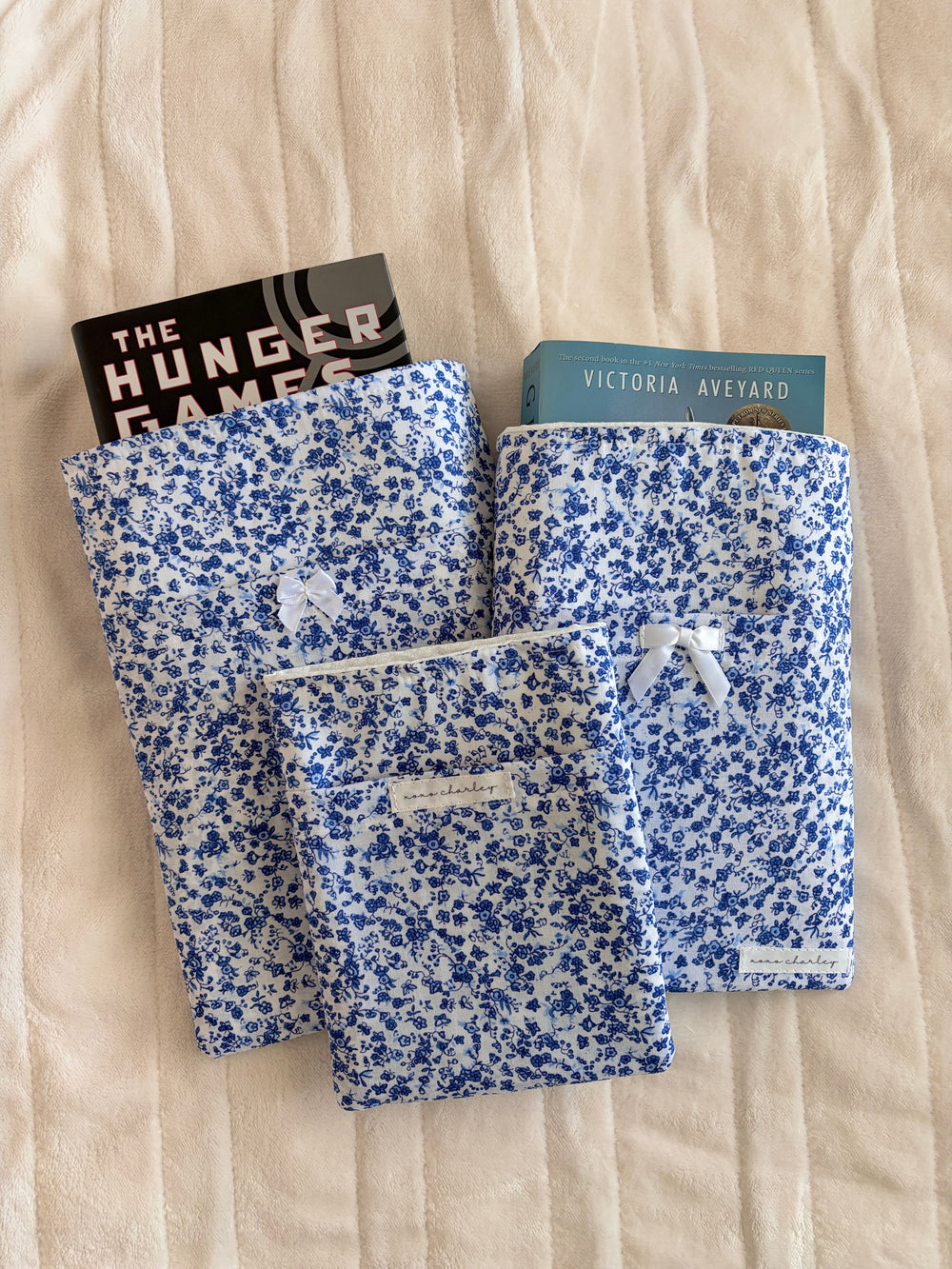 Blue floral e-reader/book sleeve with white bow, shown with stacked books
