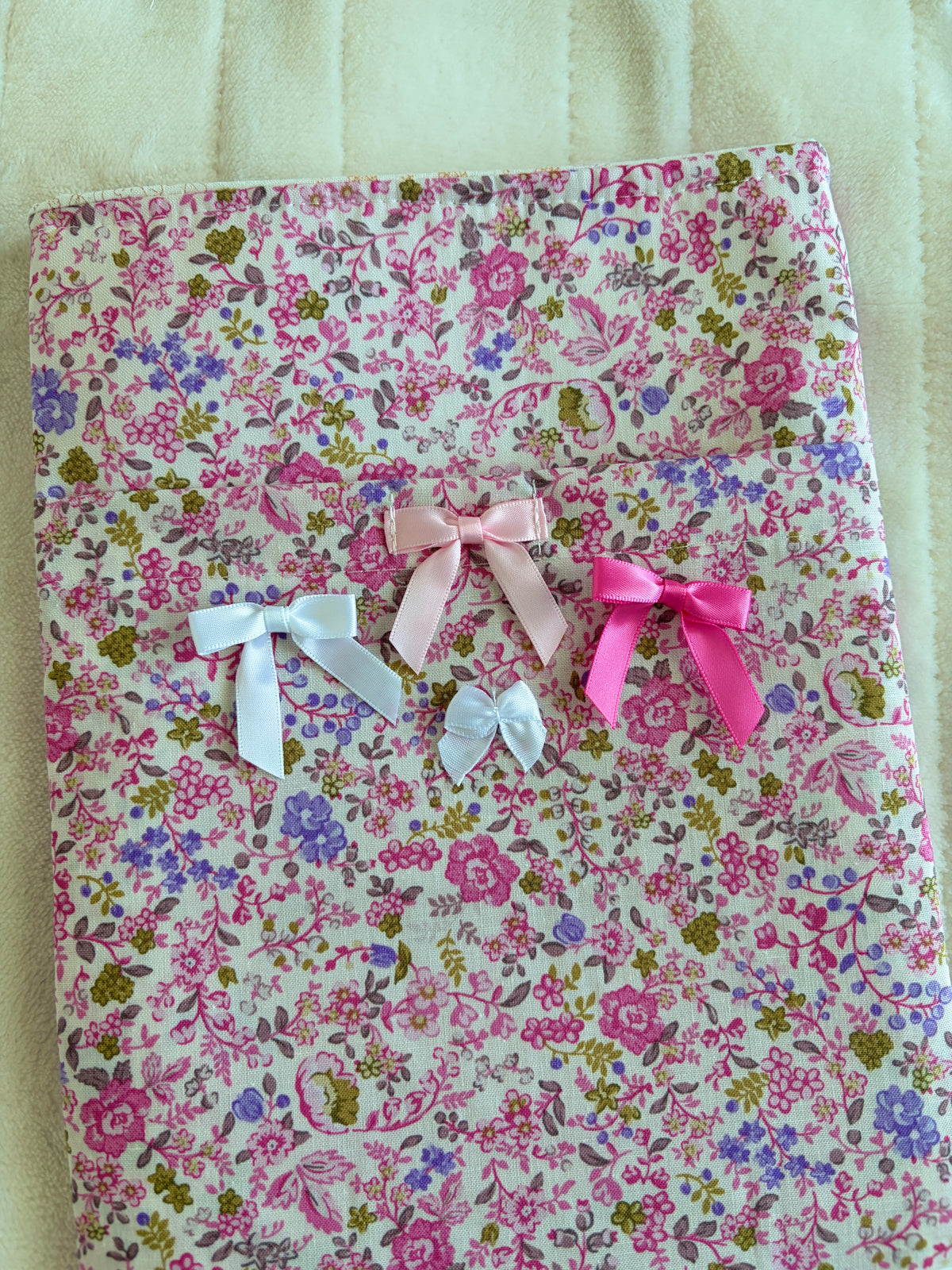 Pink floral book sleeve with multiple ribbon bows, flat