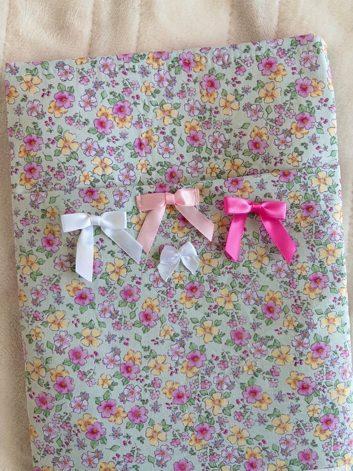 Floral e-reader/book sleeve with pink and white ribbon bows, top view