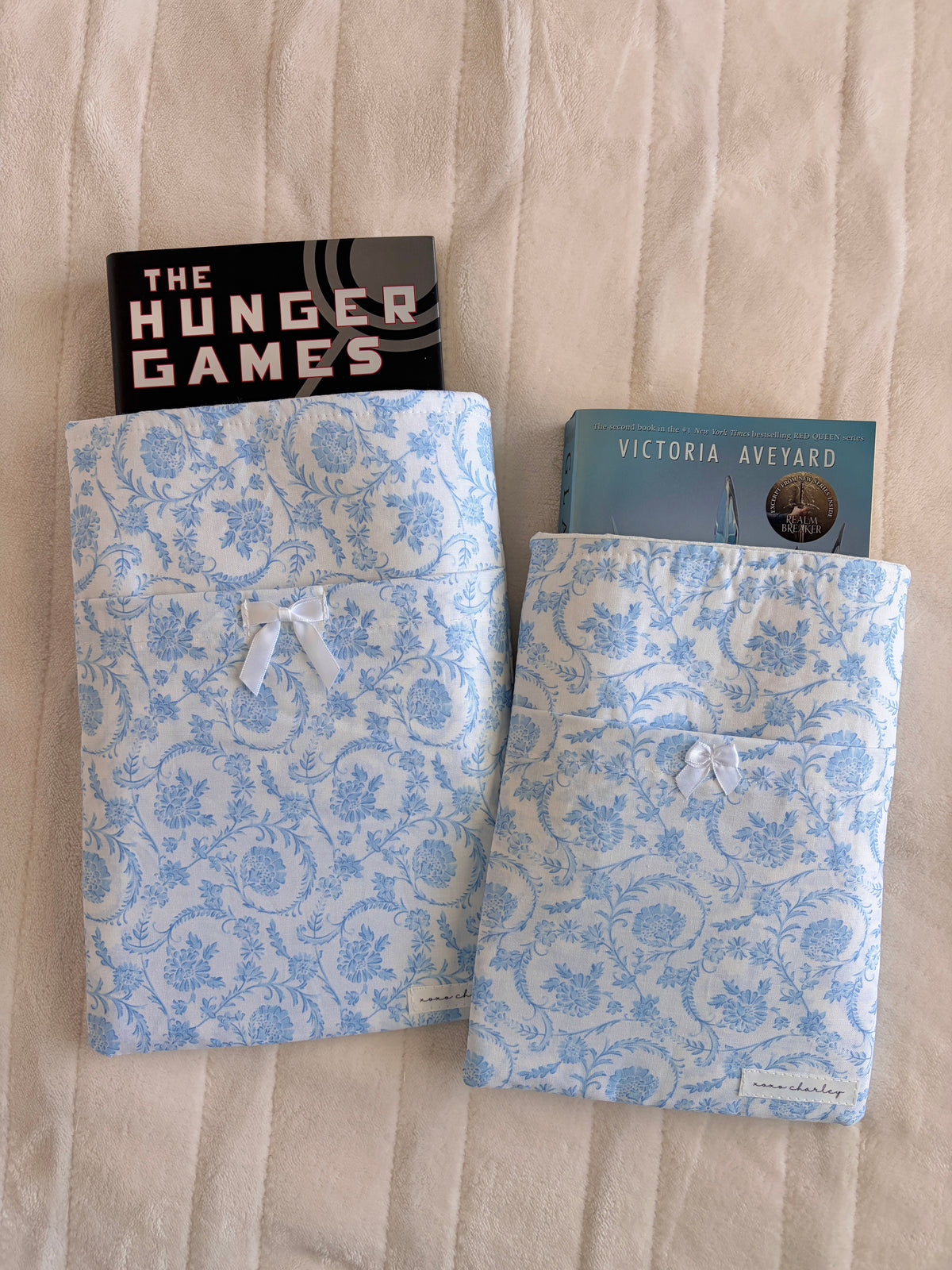 Blue floral e-reader and book sleeve holding a book and paperback