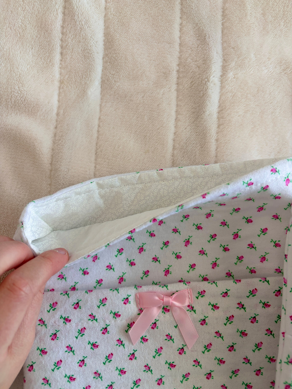 Mini rose print e-reader/book sleeve with pink ribbon bow on flap, close-up.
