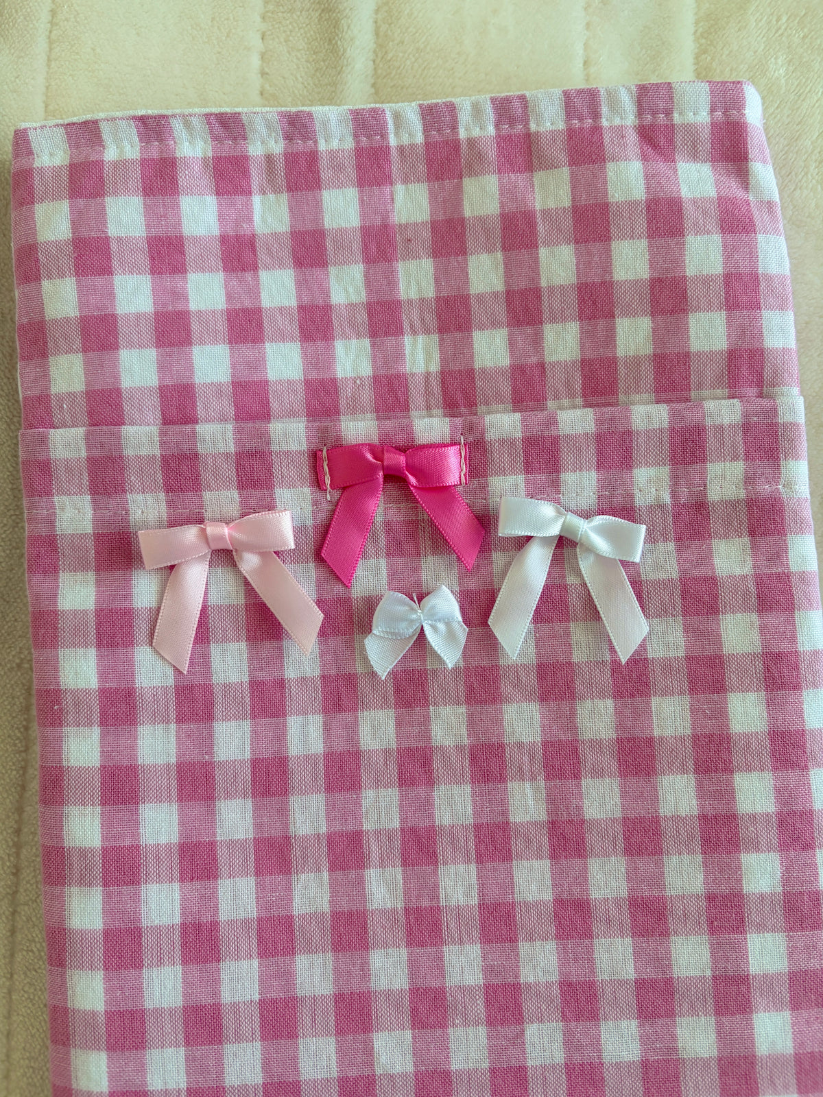 Pink gingham book sleeve with layered ribbon bows on flap