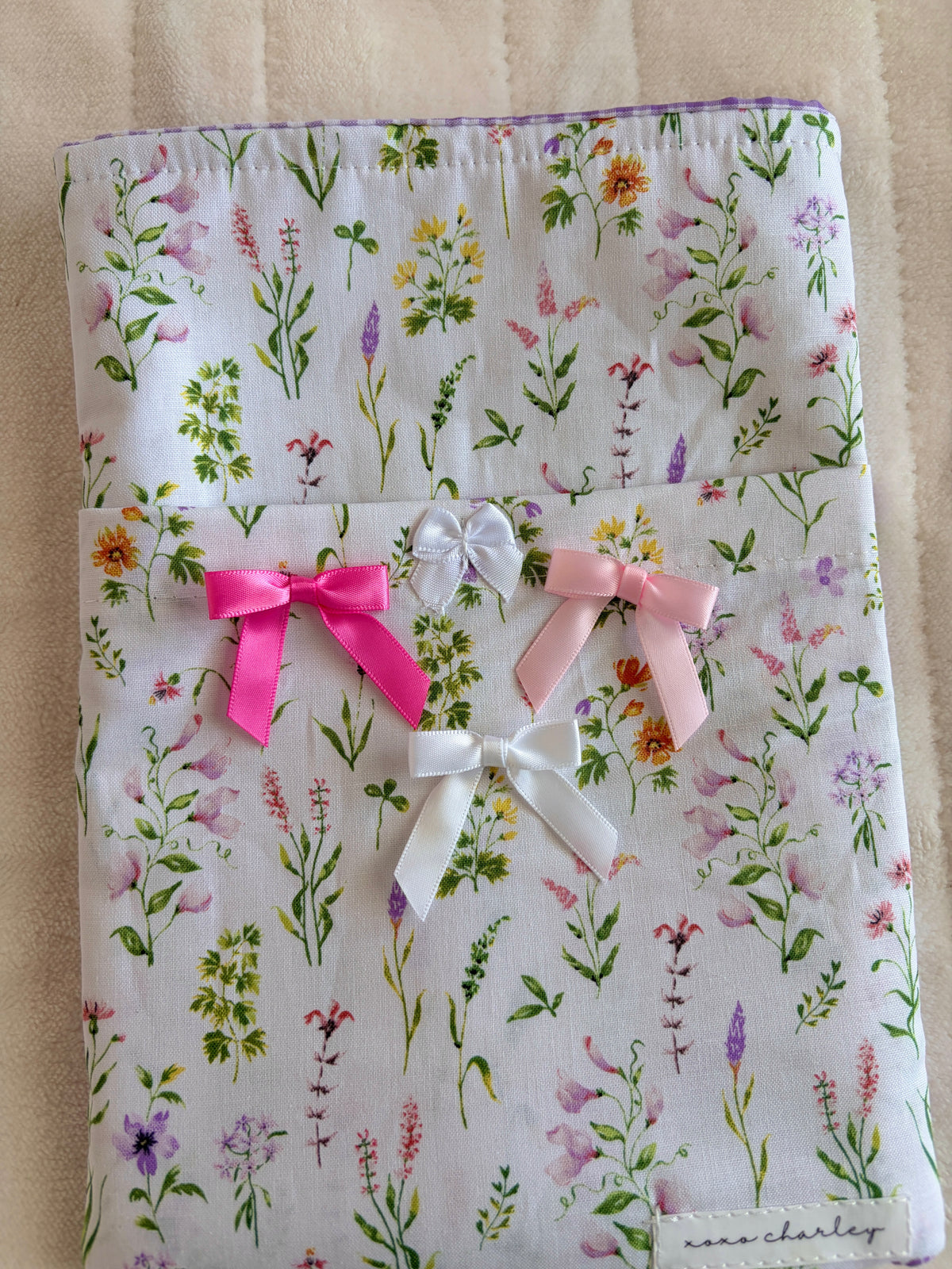 Wildflower book sleeve with three ribbon bows in pink, white, and purple