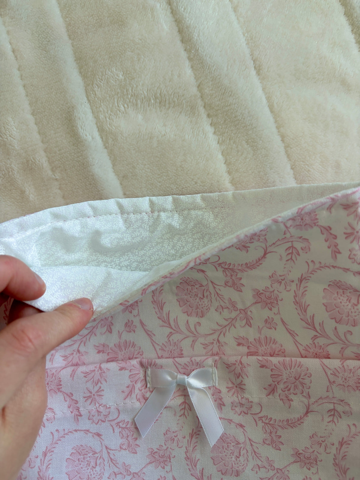Pink floral e-reader/book sleeve with white ribbon bow detail, folded close-up.