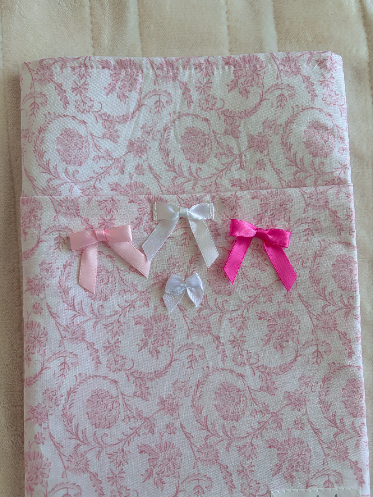 Pink floral e-reader/book sleeve with multiple ribbon bows in white and bright pink.