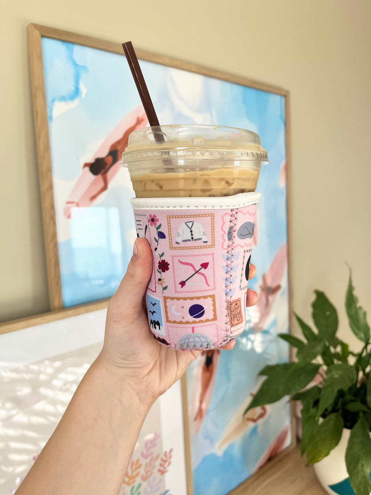 Patchwork cup sleeve with pastel collage designs, covering a takeaway cold coffee cup
