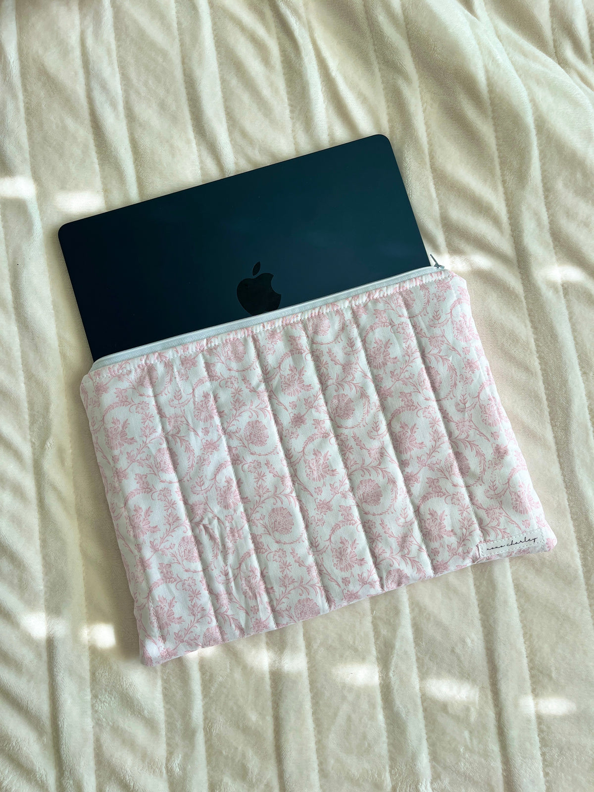 Pink patterned laptop sleeve with dark tablet inside, front gathered opening.