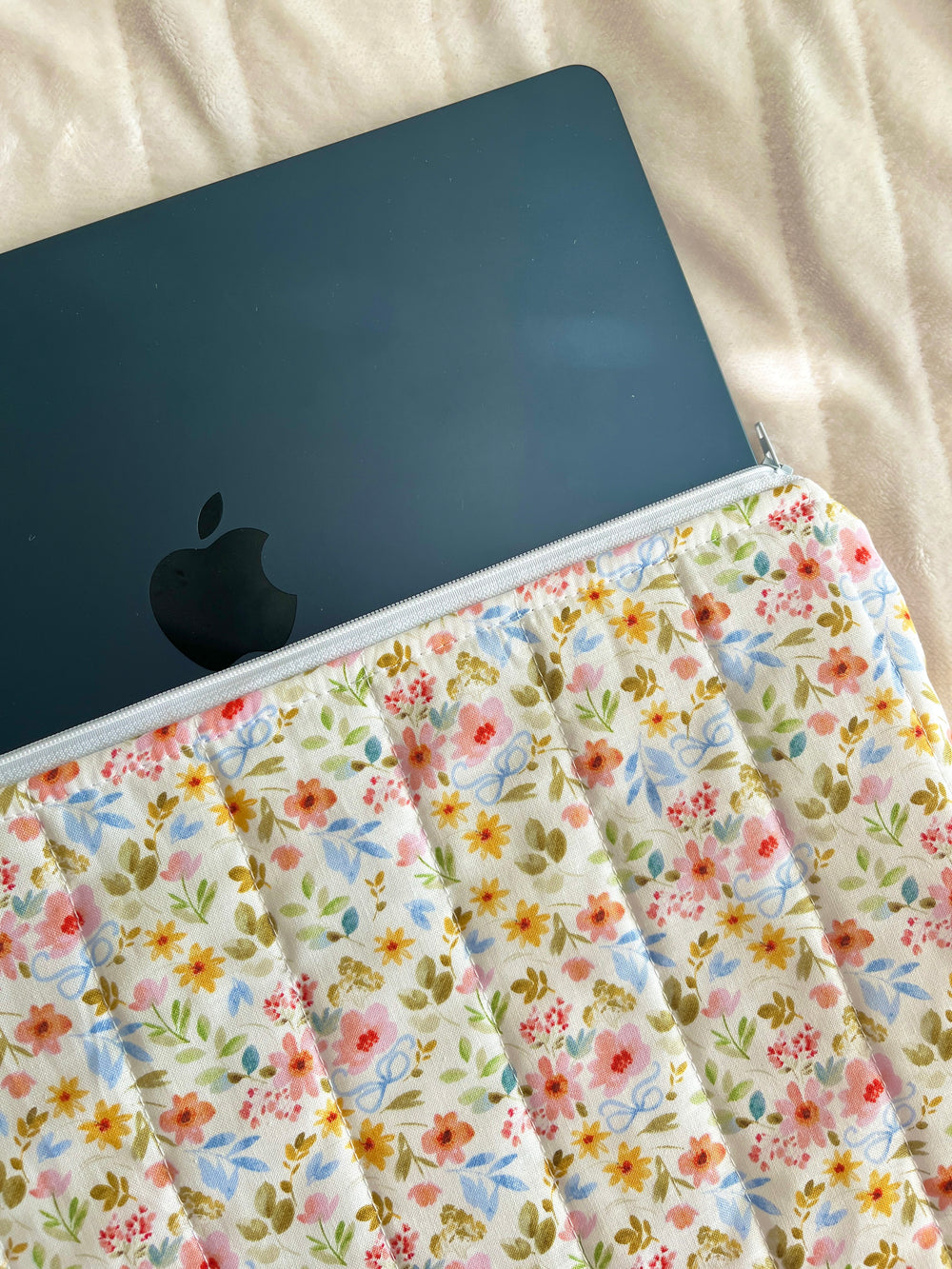 Floral laptop sleeve with zipper opening and dark laptop partially inside