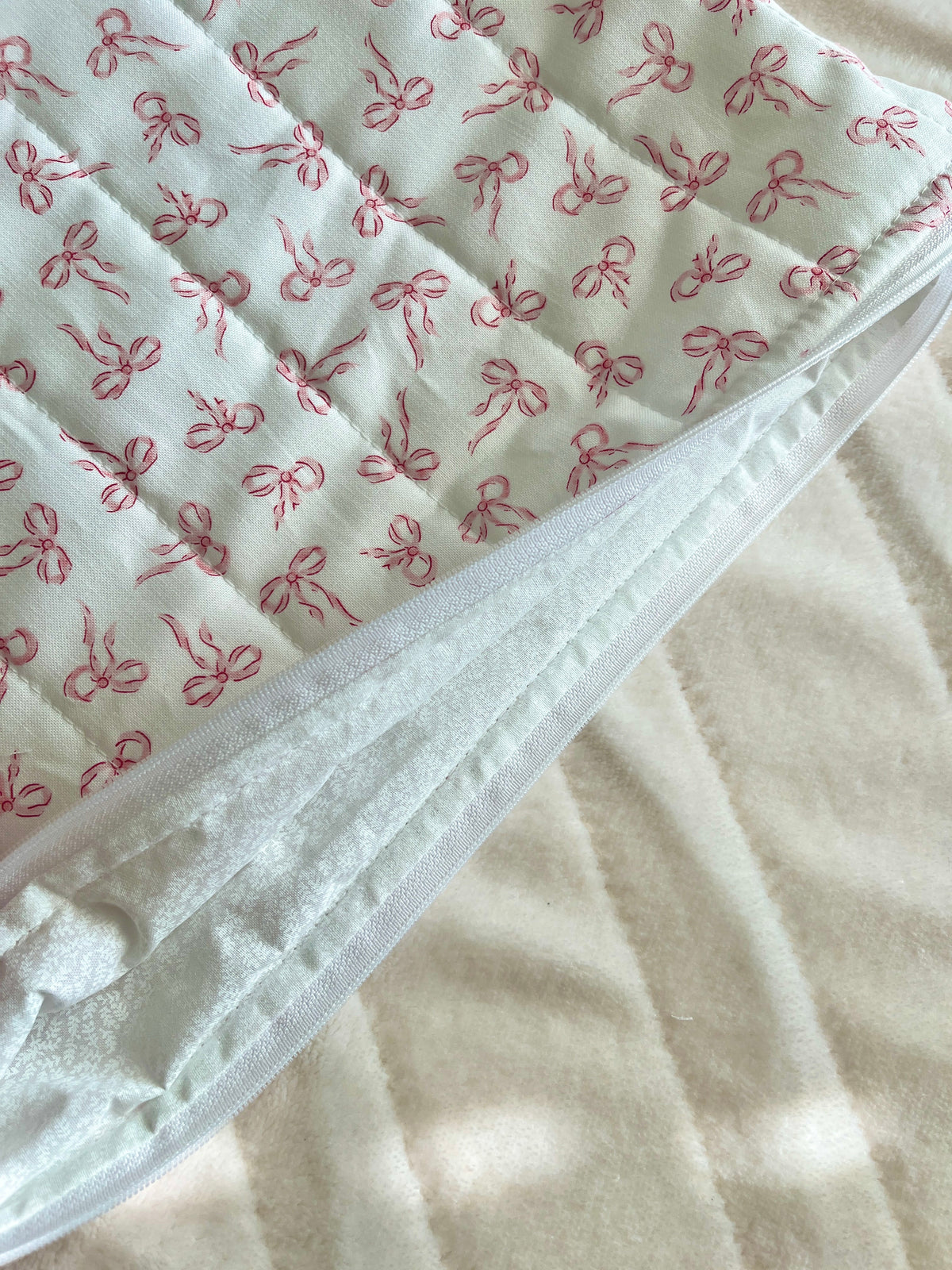 Mini laptop and tablet sleeve fabric close-up: white base with repeating pink bow print