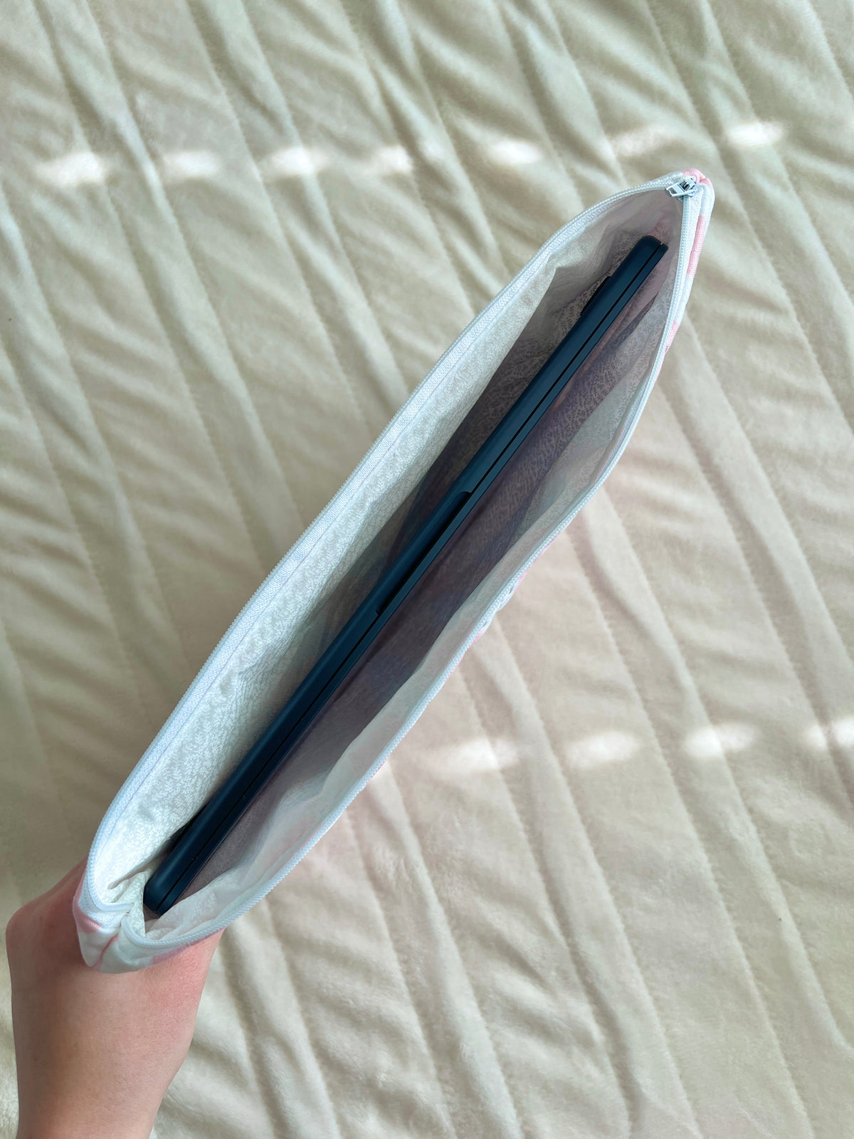 Pink and white striped laptop and tablet sleeve, shown in a hand