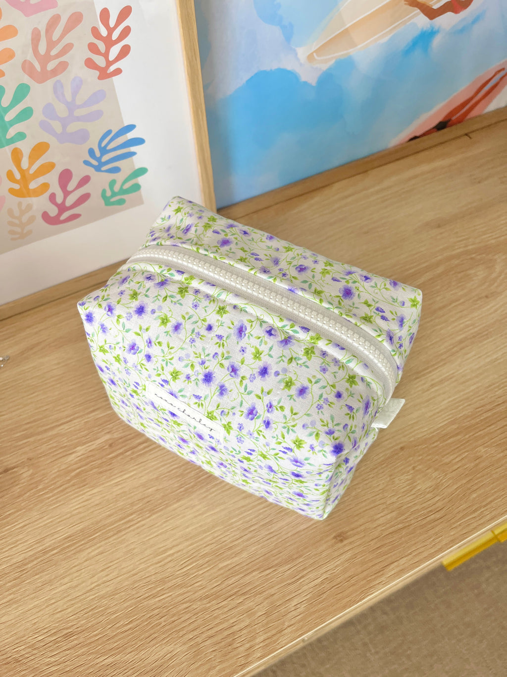 Medium floral makeup bag, purple and white print, angled view with zipper