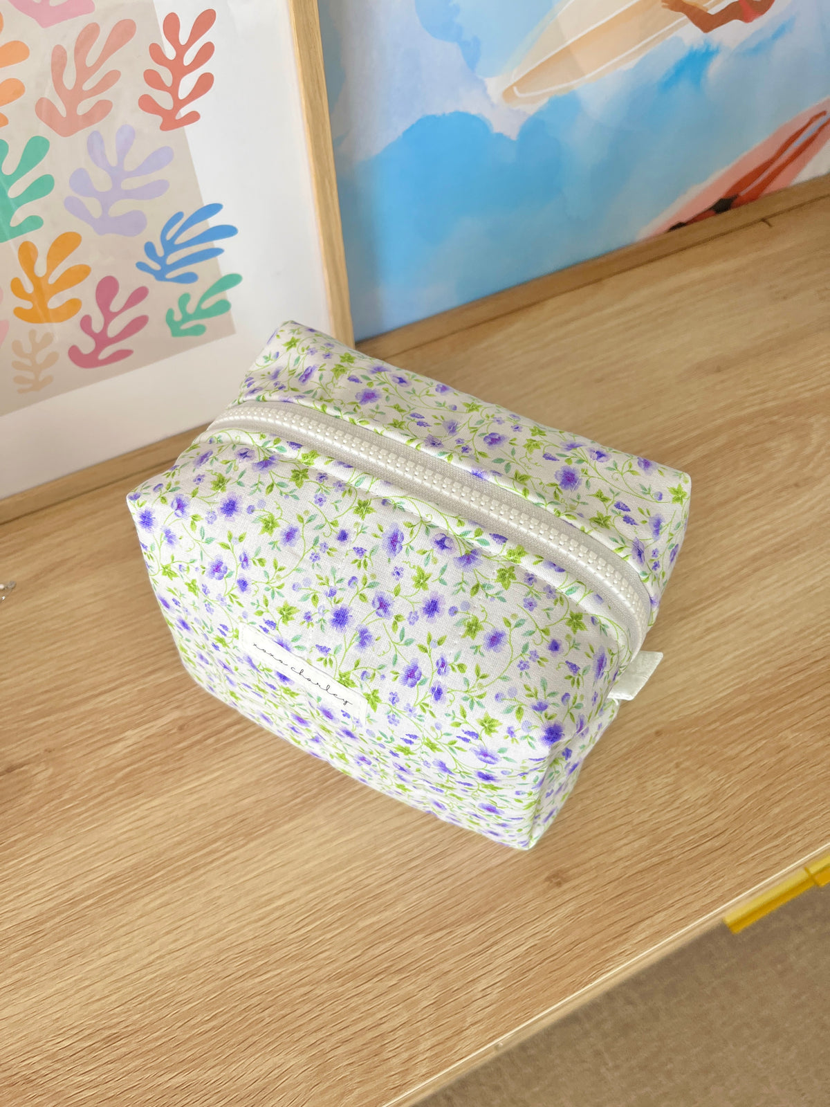 Medium floral makeup bag, purple and white print, angled view with zipper