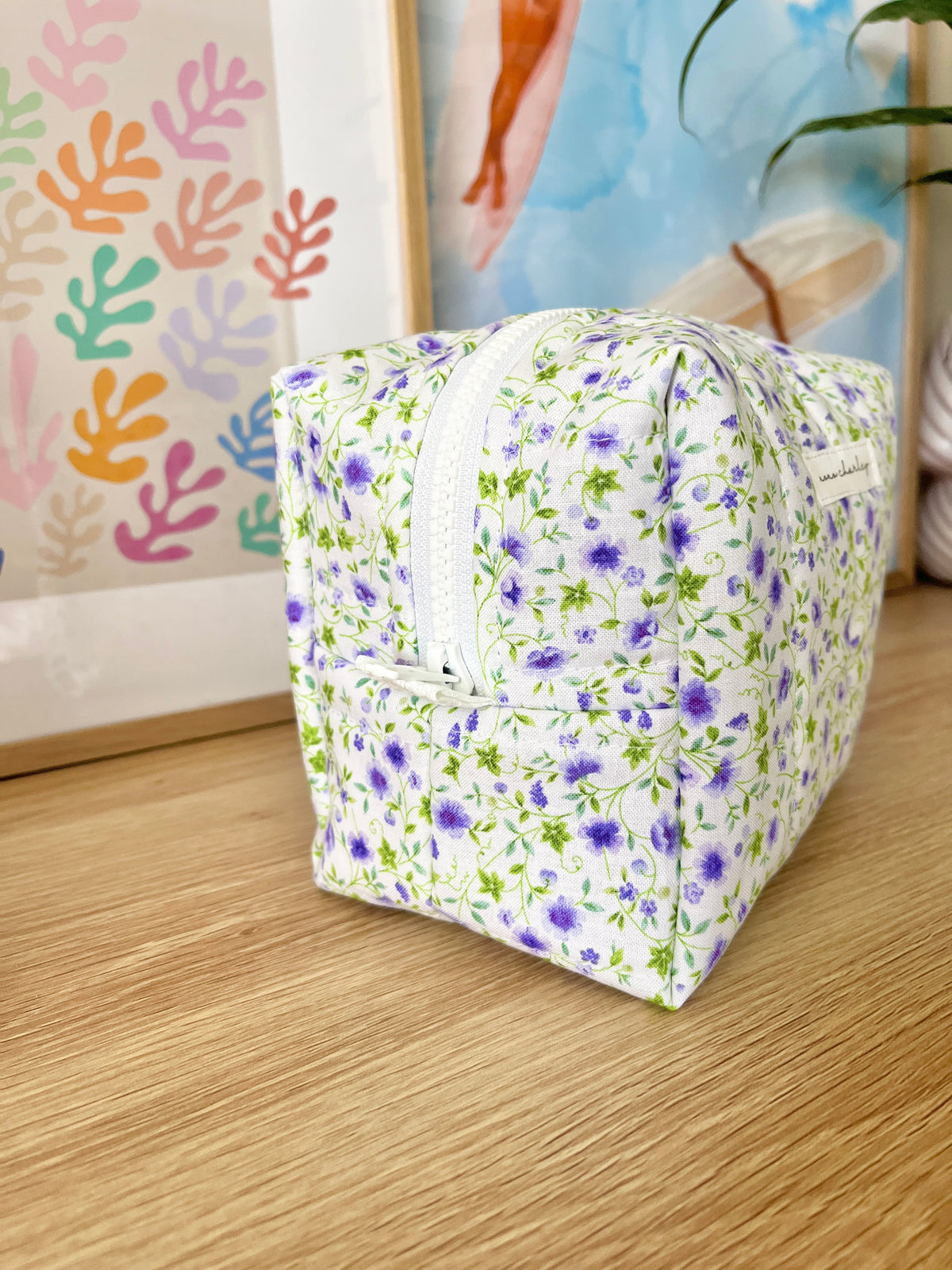Medium floral makeup bag, purple and white print, front label patch and zipper