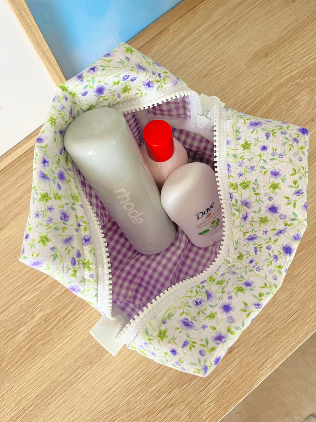 Medium floral makeup bag open, purple check lining and soap bottles inside