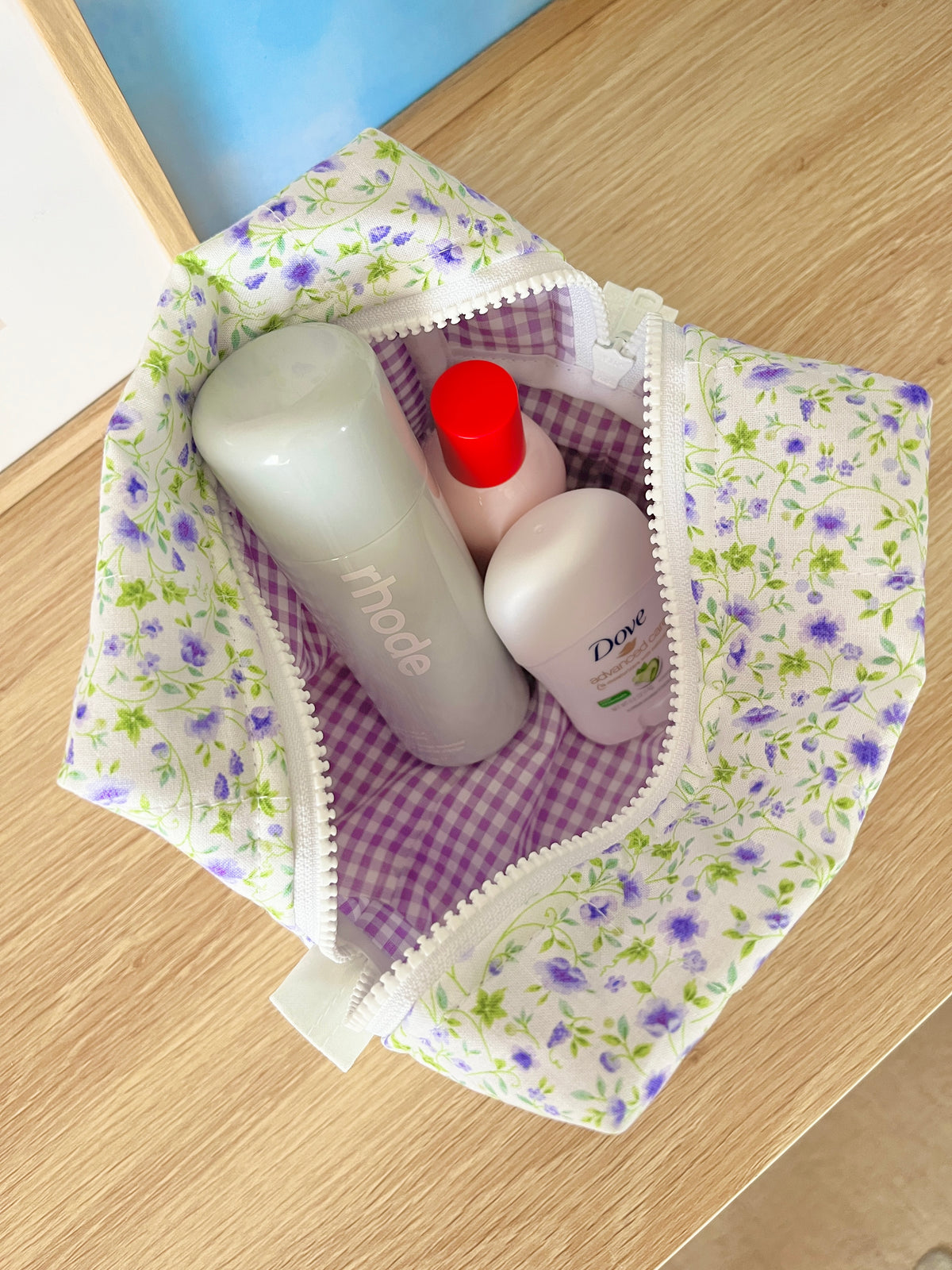 Medium floral makeup bag open, purple check lining and soap bottles inside