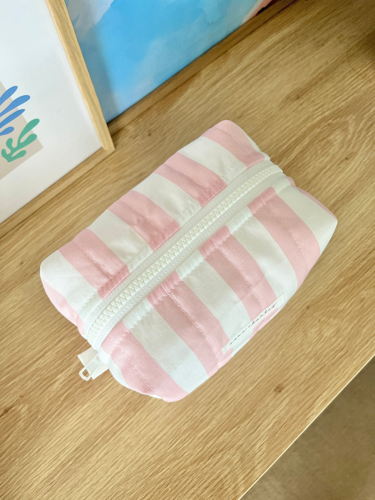 Pink and white striped medium makeup bag with white zipper top and tassel pull.