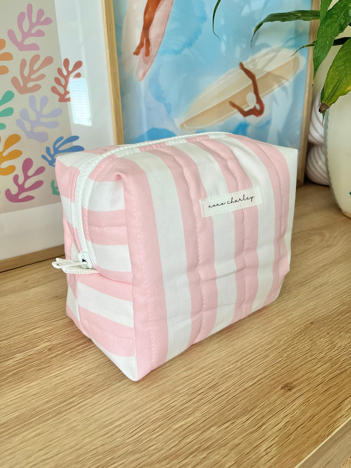 Pink and white striped medium makeup bag with white zipper and stitched front panel.