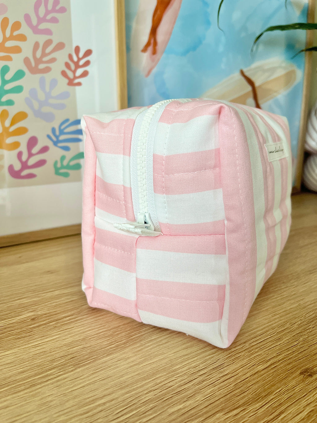 Pink and white striped medium makeup bag with front pocket and centered zipper.