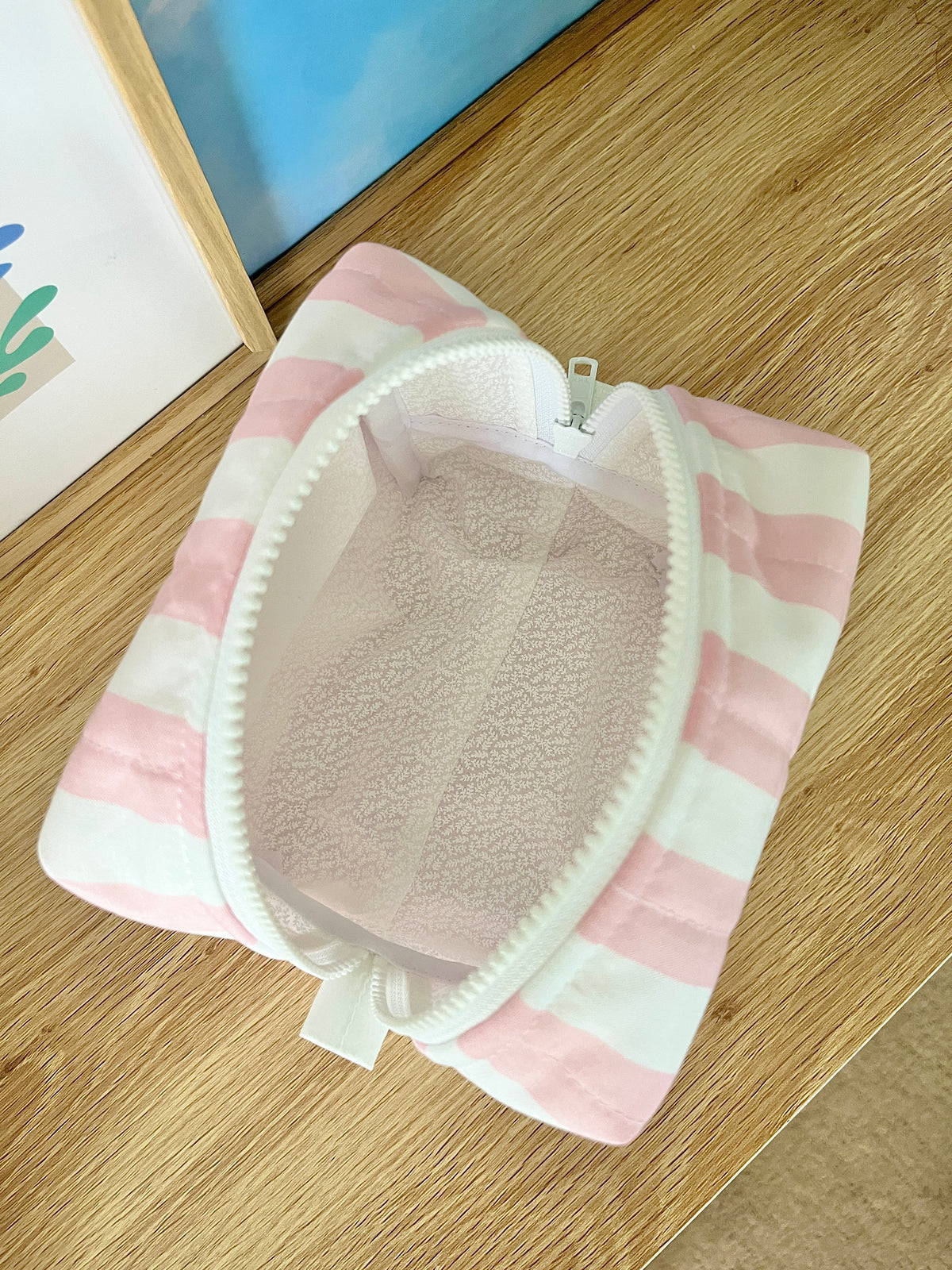Pink and white striped makeup bag open, showing light interior lining and zipper.
